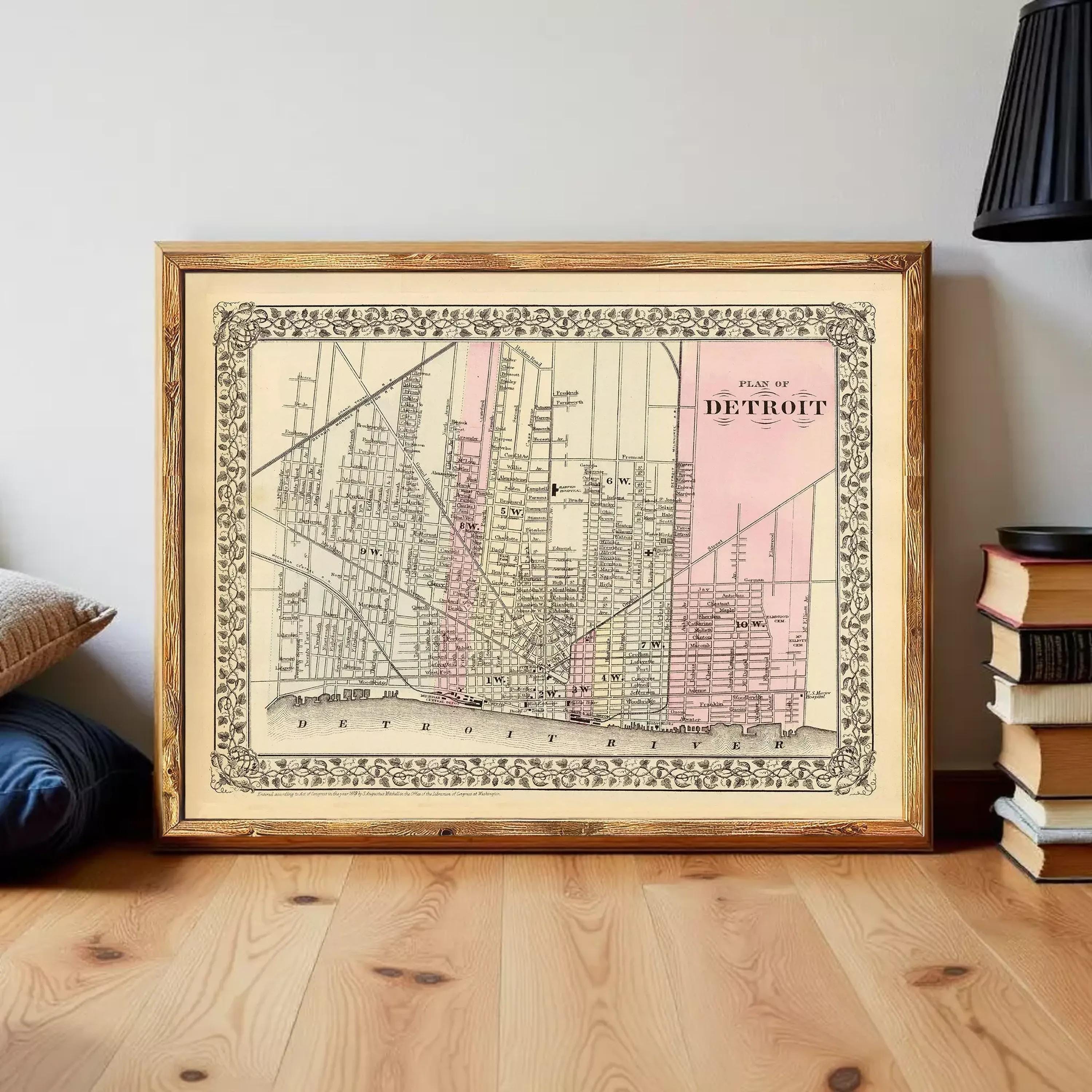 A framed map of Detroit, Michigan, with a vintage style and a pink background.