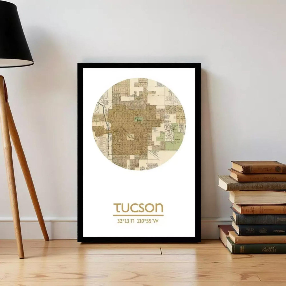 A framed map of Tucson, Arizona, with the city's name and location displayed, is placed on a wall next to a stack of books.