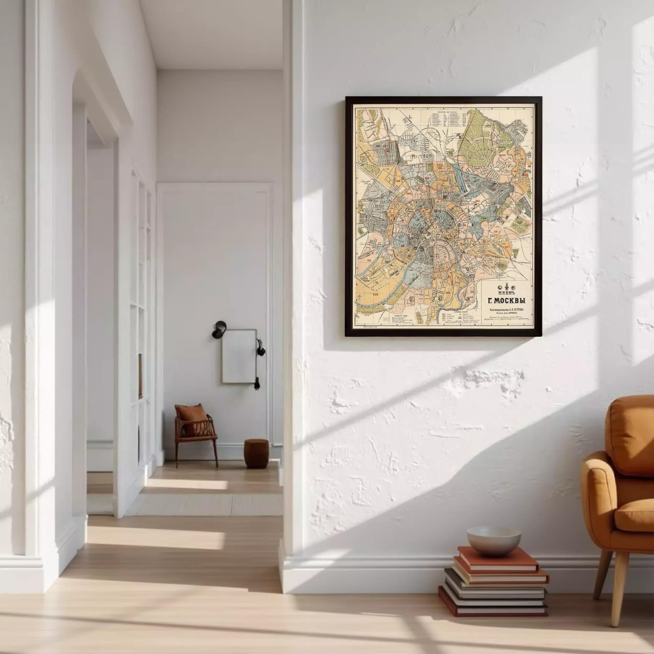 a living room with a large framed map of Moscow hanging on the wall. The room has a white color scheme and includes a chair, a stack of books, and a bowl on the floor.