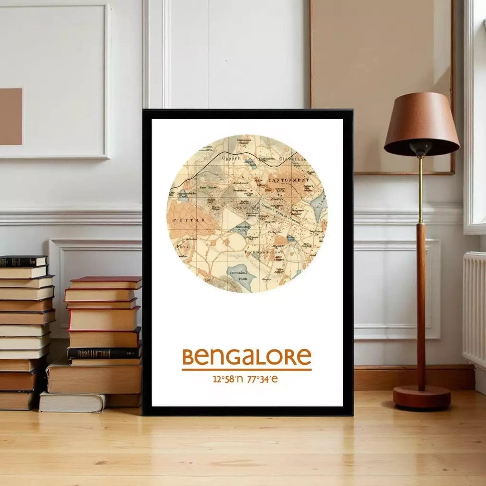 A framed map of India, specifically highlighting the city of Mumbai, is displayed on a wooden floor in a room with books and a lamp.