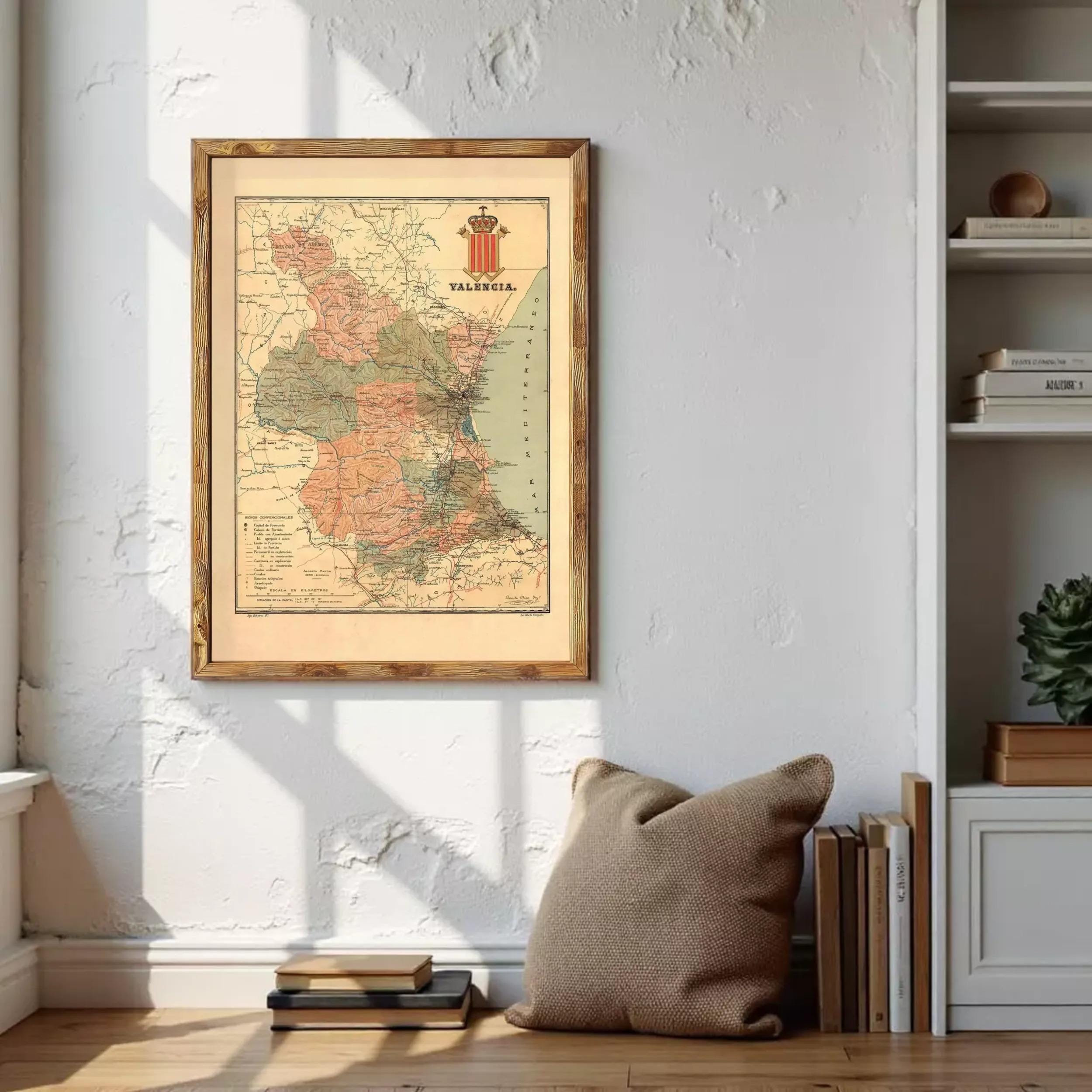 a framed map of Germany hanging on a wall, with a stack of books and a pillow placed in front of it.