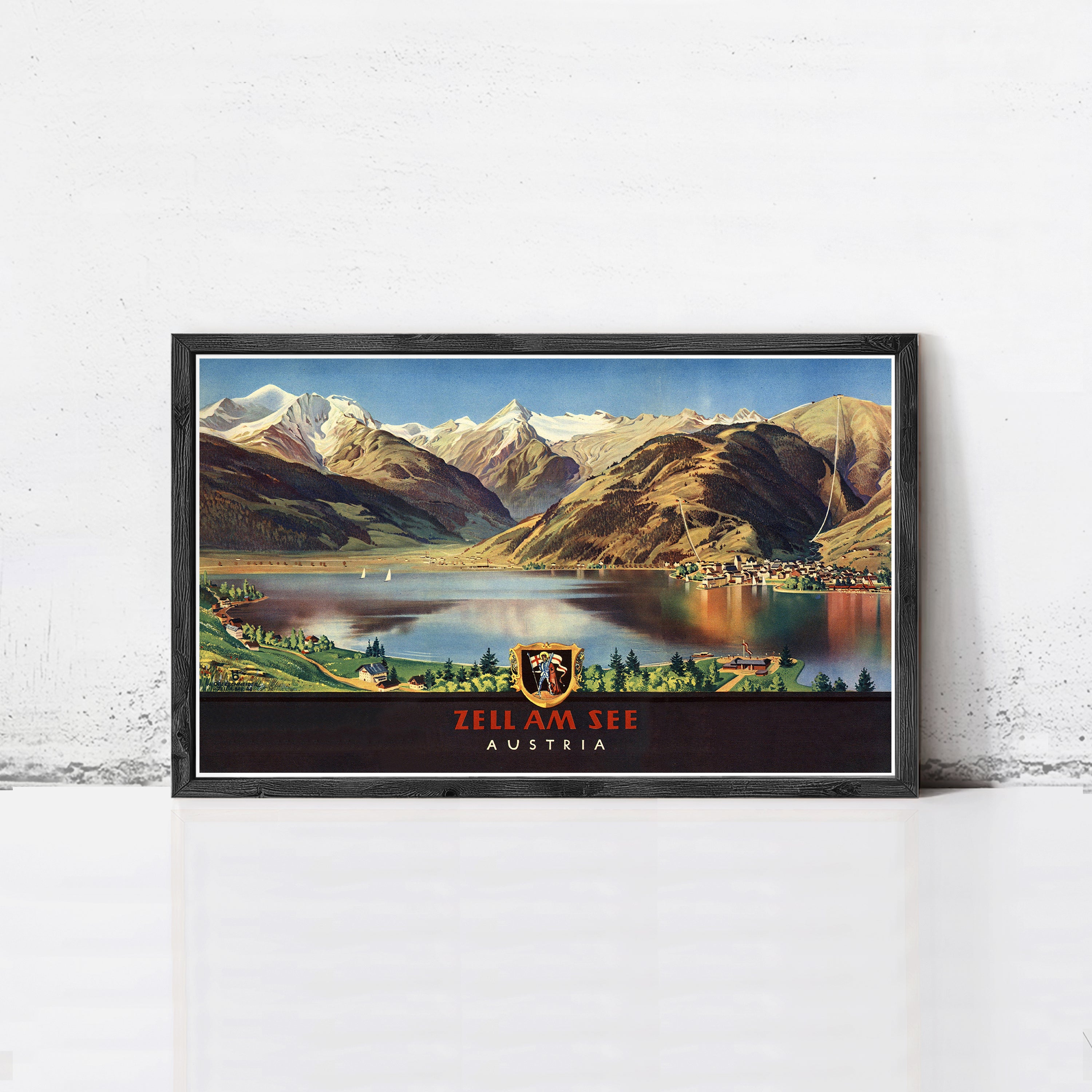 A framed vintage poster depicting a scenic mountain landscape with a lake and a town in the foreground, with the text "ZELL AM SEE AUSTRIA" prominently displayed.