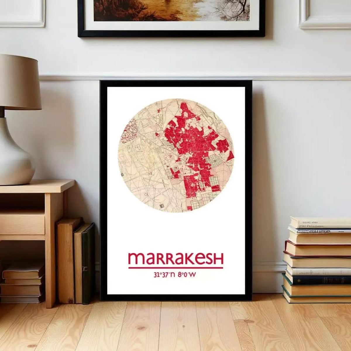 A framed map of Marrakech, Morocco, with a red and white color scheme, is displayed on a wall in a room with a lamp and bookshelf.