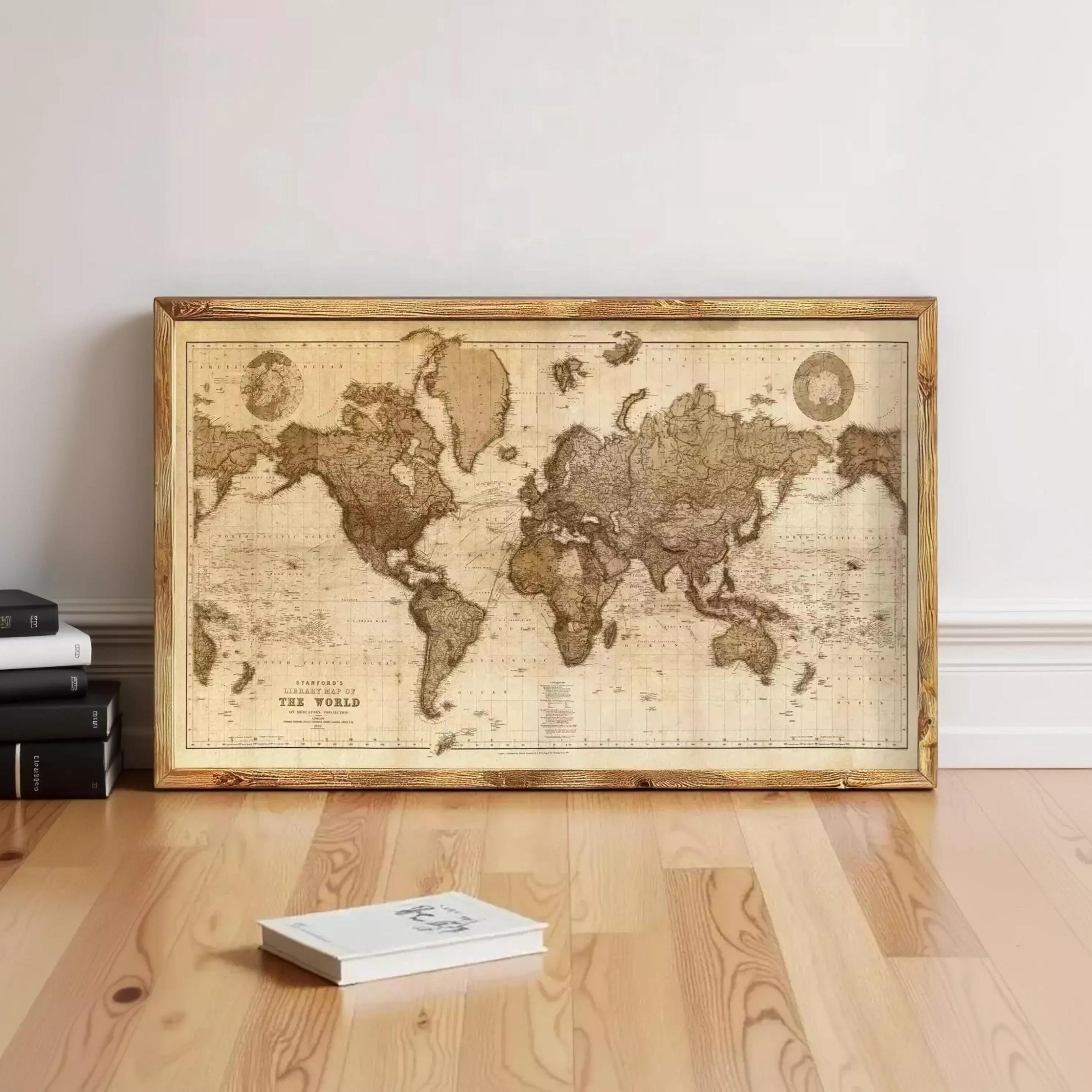 a large world map displayed on a wooden floor, with a stack of books and a book lying nearby.