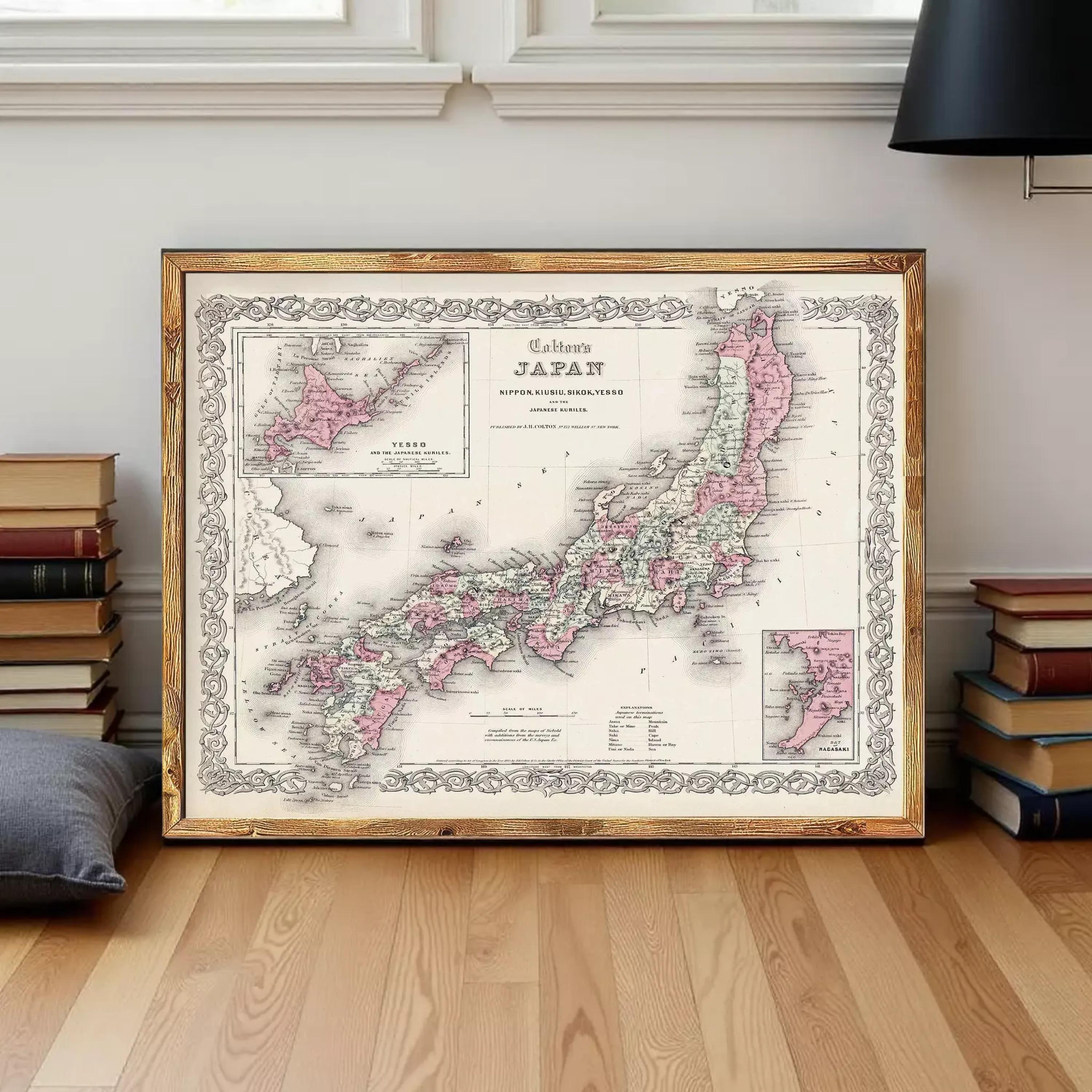 a framed map of Japan, with a wooden floor and a stack of books in the background.