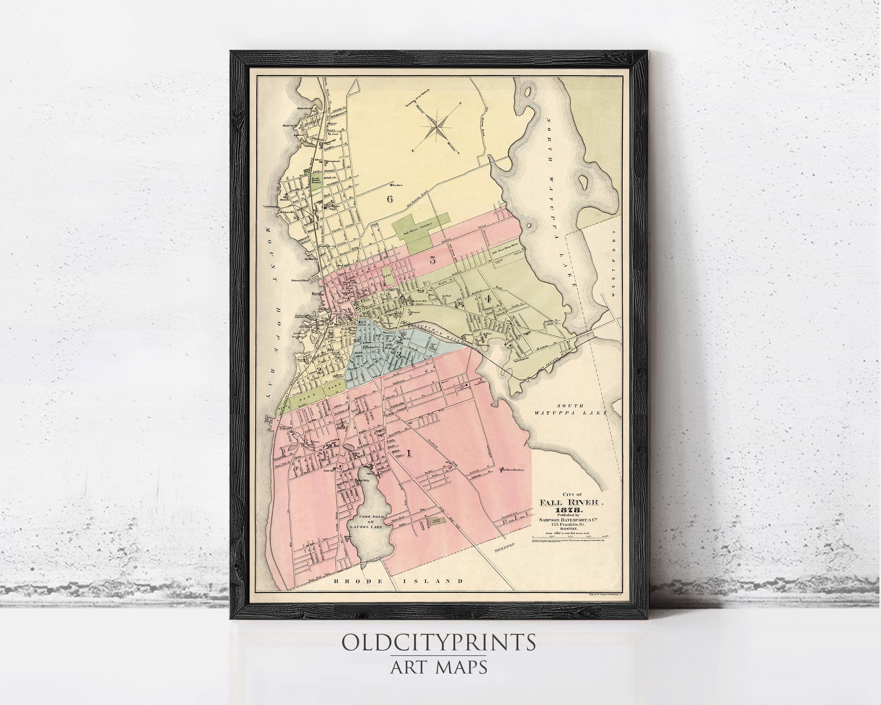 The image is a framed vintage map of a city, likely from the late 19th century, with various colored areas representing different neighborhoods or districts.