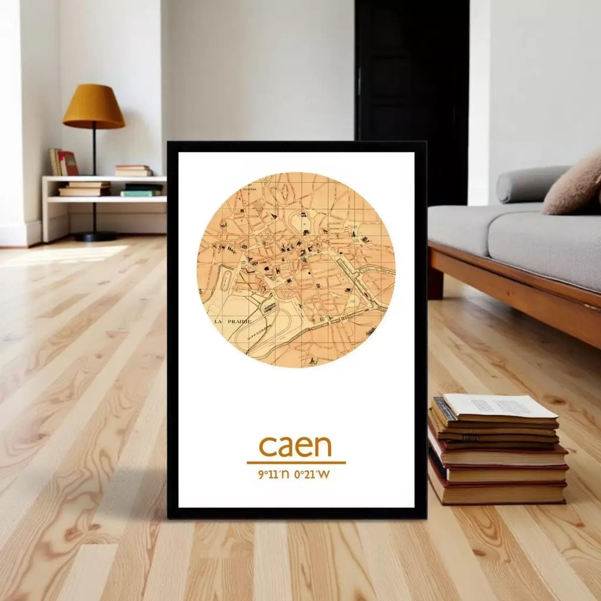 A framed map of Caen, France, with the word "caen" written below it, is displayed on a wooden floor in a living room setting.