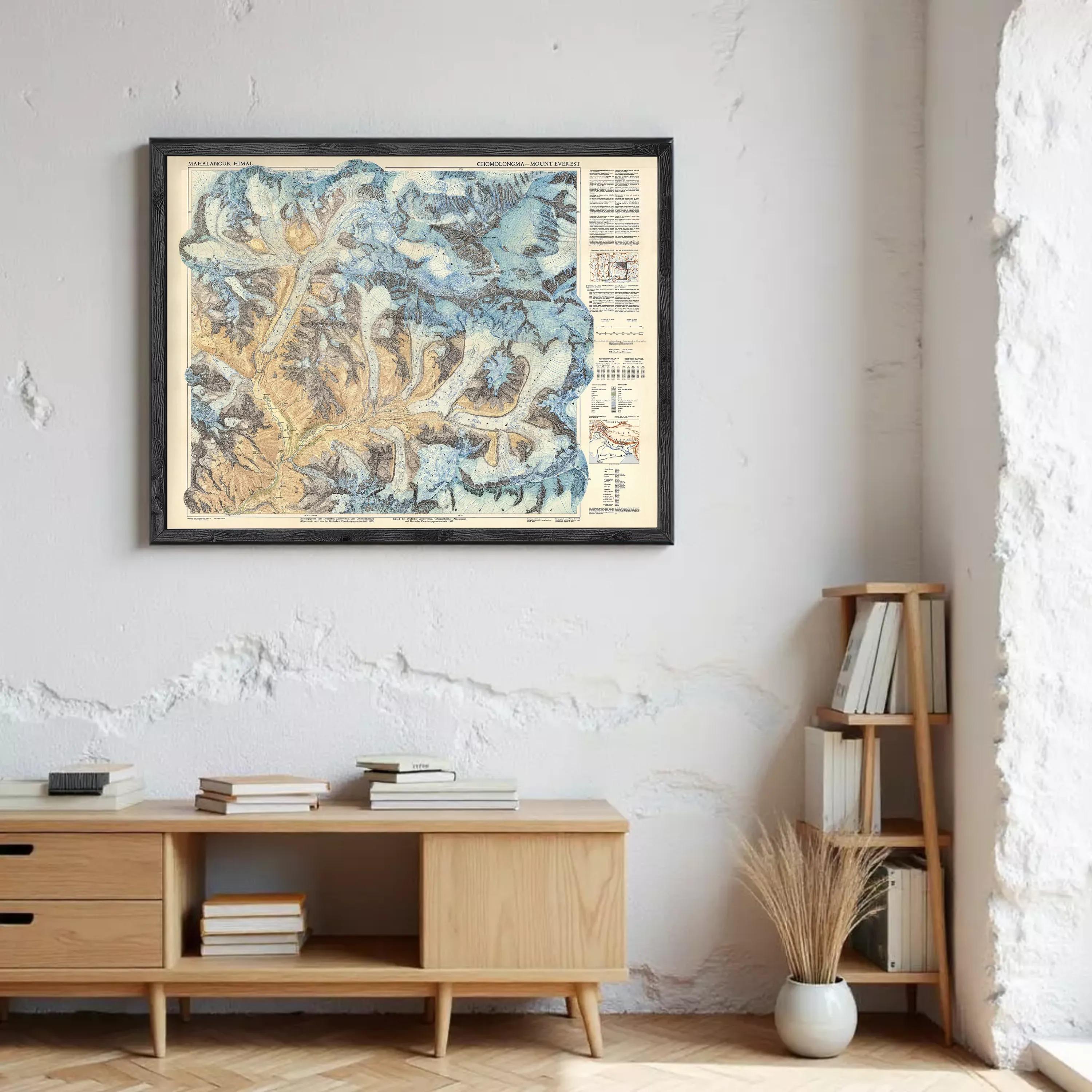 a framed map of the Rocky Mountains hanging on a wall, with a wooden cabinet below it and a bookshelf to the right.