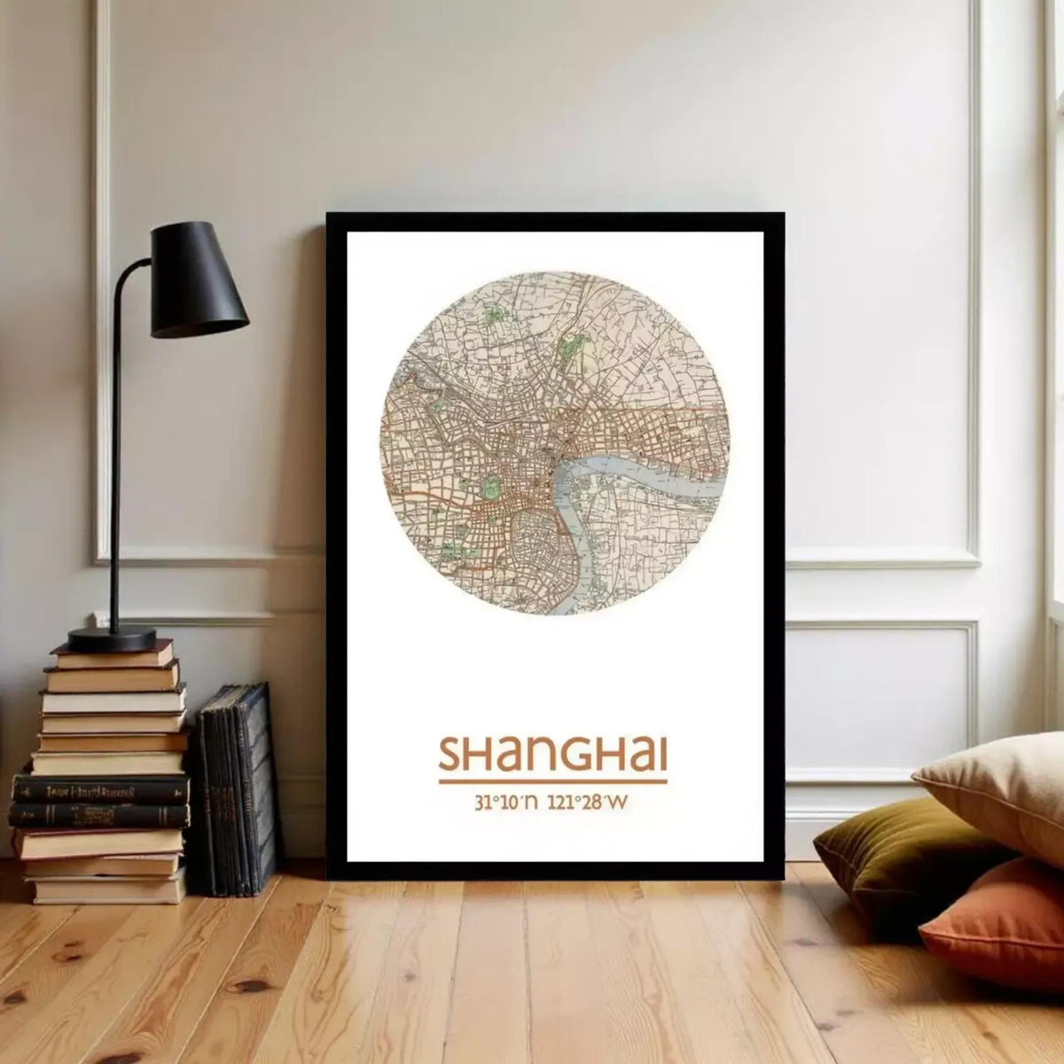 A framed map of Shanghai, China, with the text "Shanghai" and the date "31.11.21" and "21.28.20" printed on it, is displayed on a wall in a room with a lamp, books, and pillows.