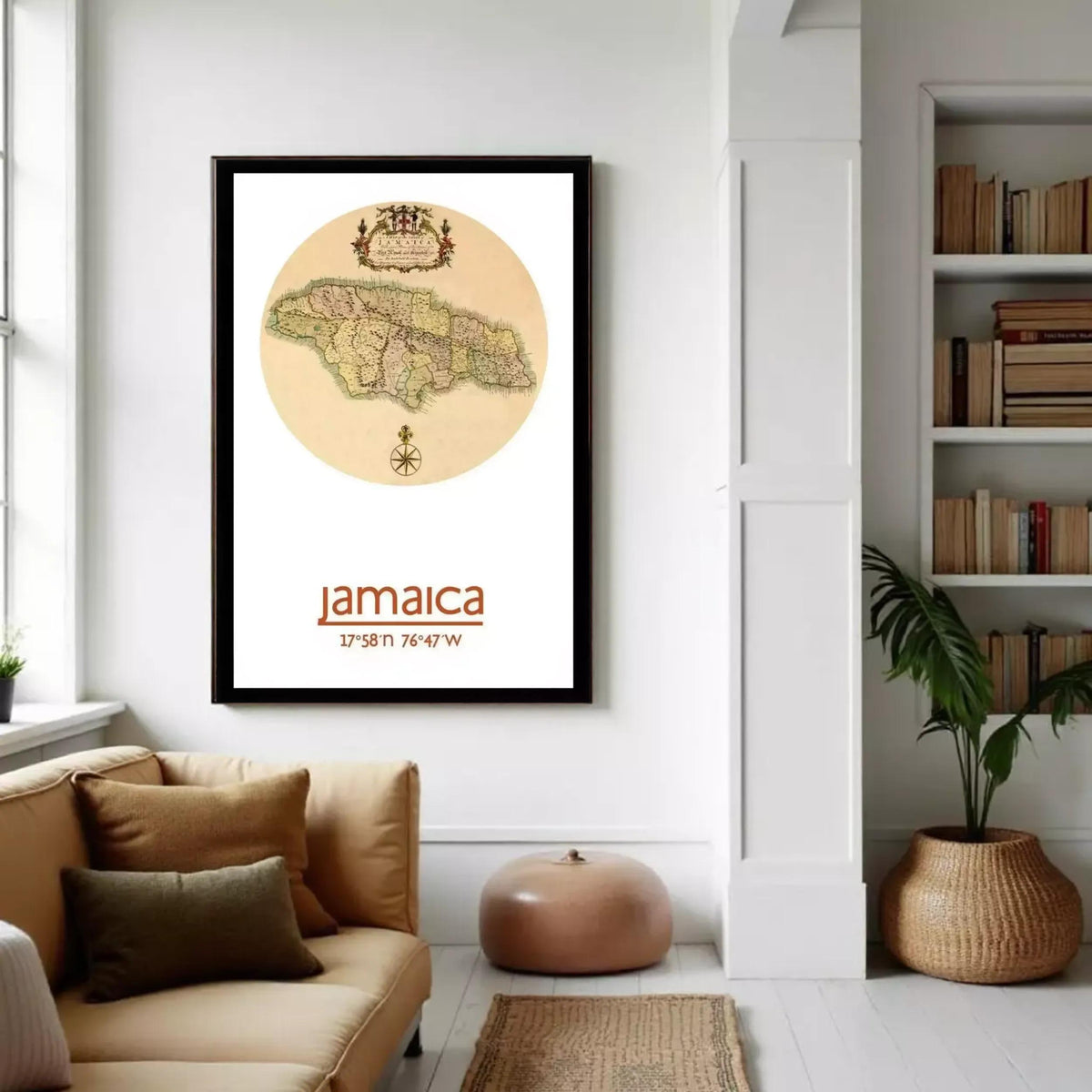 A framed map of Jamaica hangs on a white wall in a cozy living room, with a bookshelf and a potted plant nearby.
