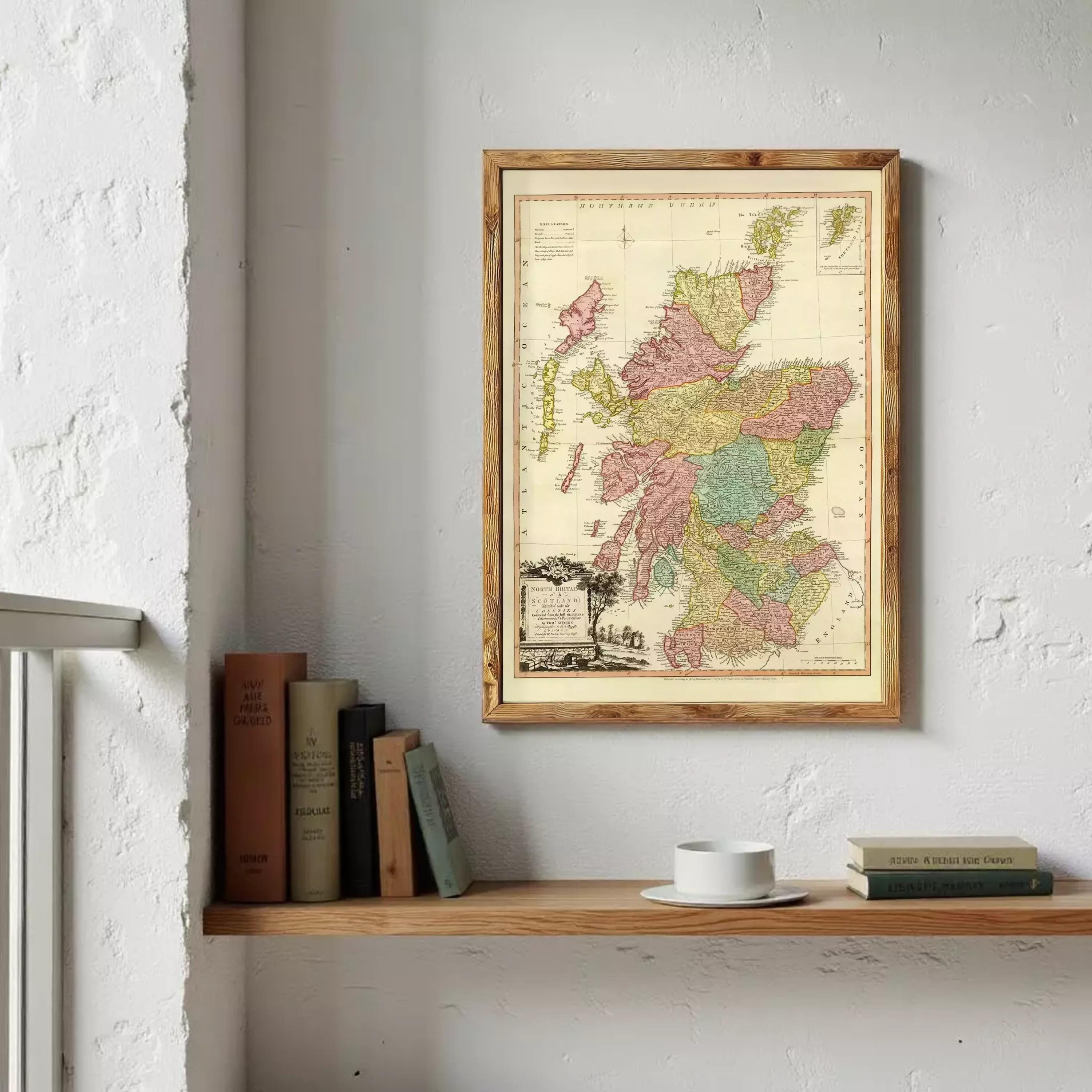 a wooden shelf with a framed map of Scotland hanging on the wall above it. The shelf also holds several books and a white coffee cup.