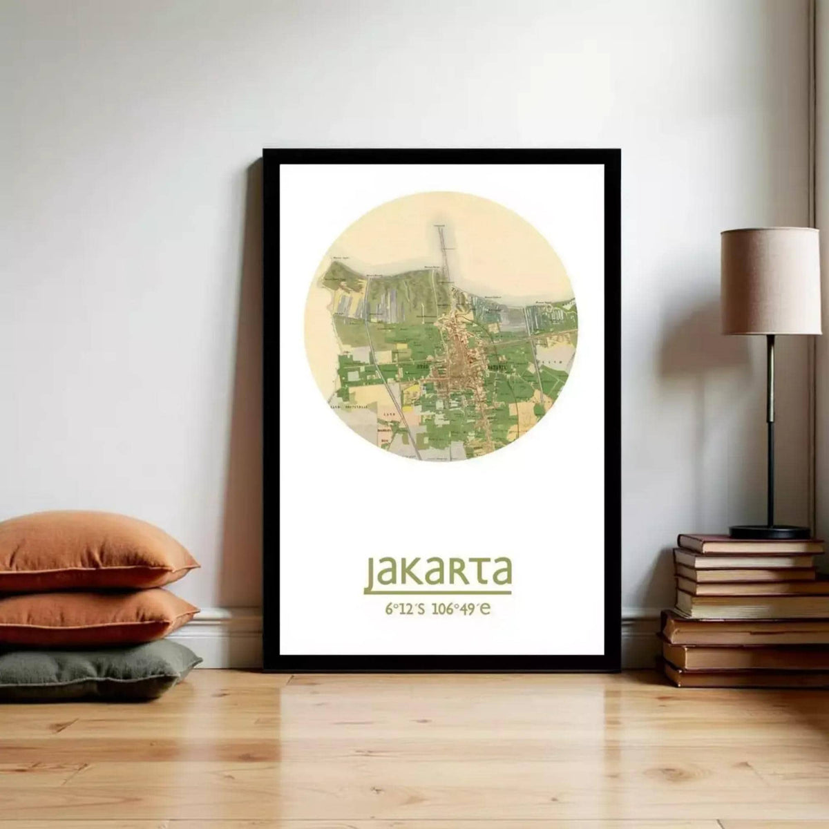 A framed poster of a map of Jakarta, Indonesia, displayed on a wall next to a stack of books and a lamp.