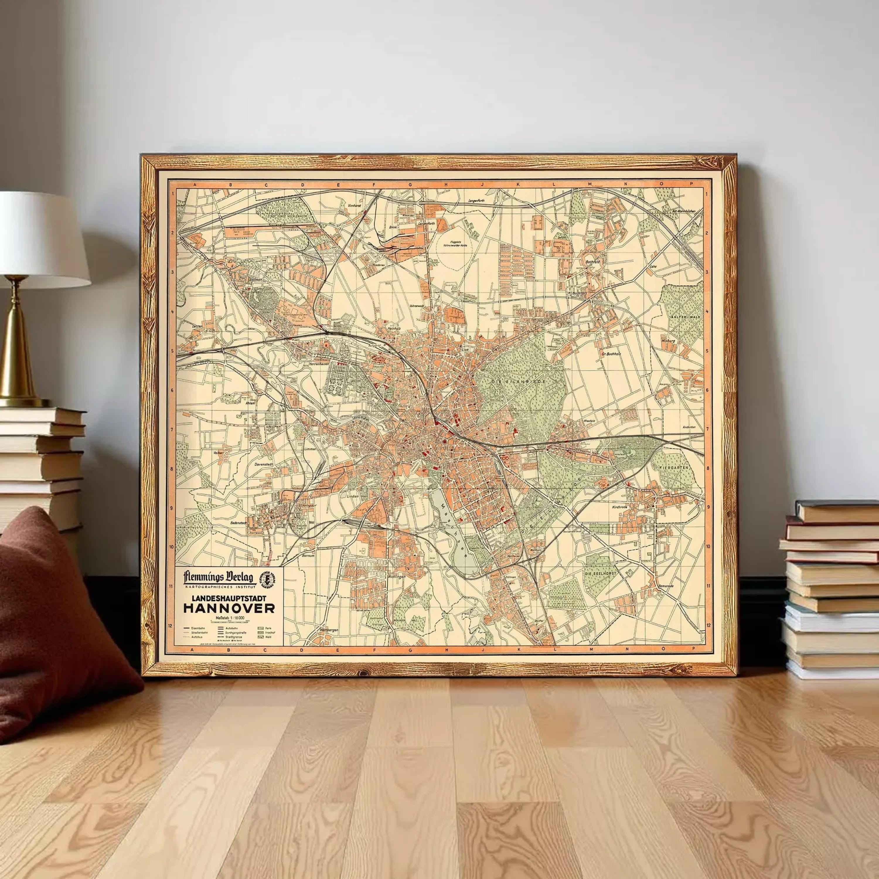 a large framed map of Hantaan, Germany, with a wooden frame and a vintage style. The map is displayed on a wooden floor, surrounded by a stack of books and a lamp.