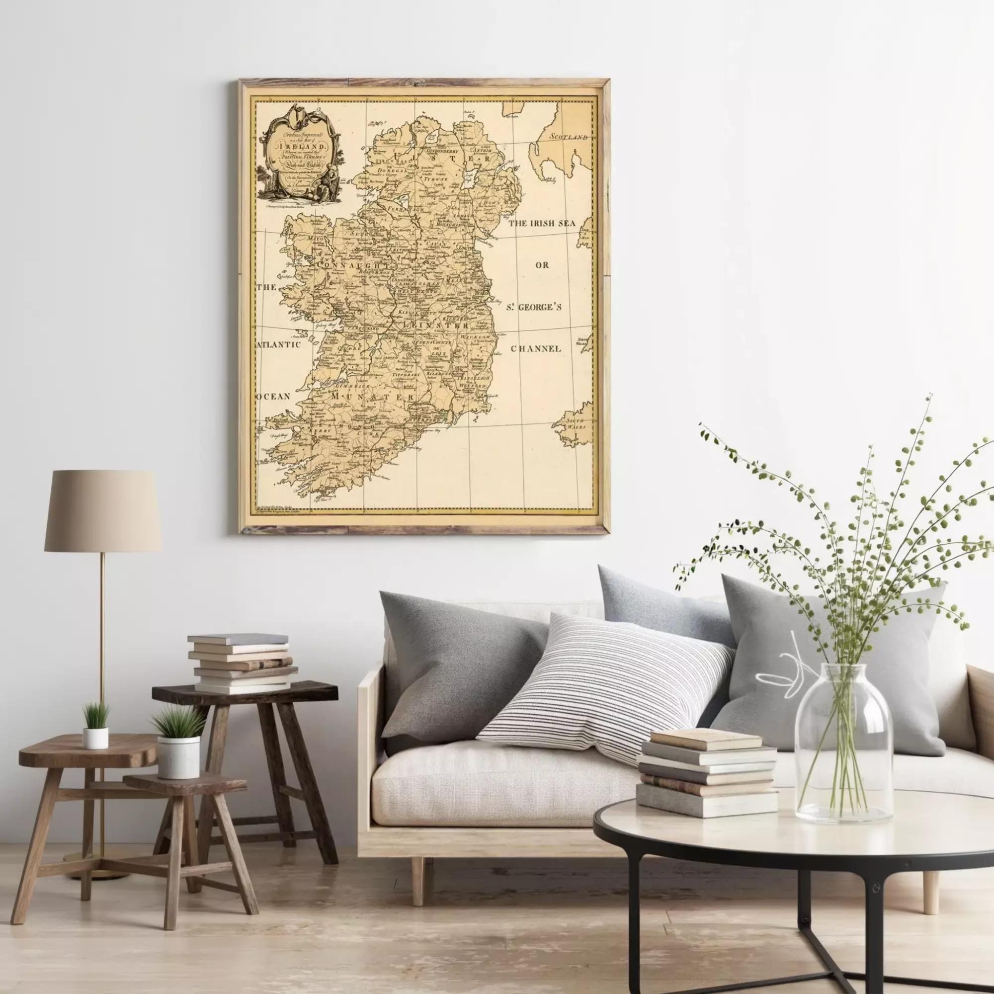 a living room with a large framed map of Ireland hanging on the wall above a couch with pillows. There are also some books and decorative items on the coffee table in front of the couch.