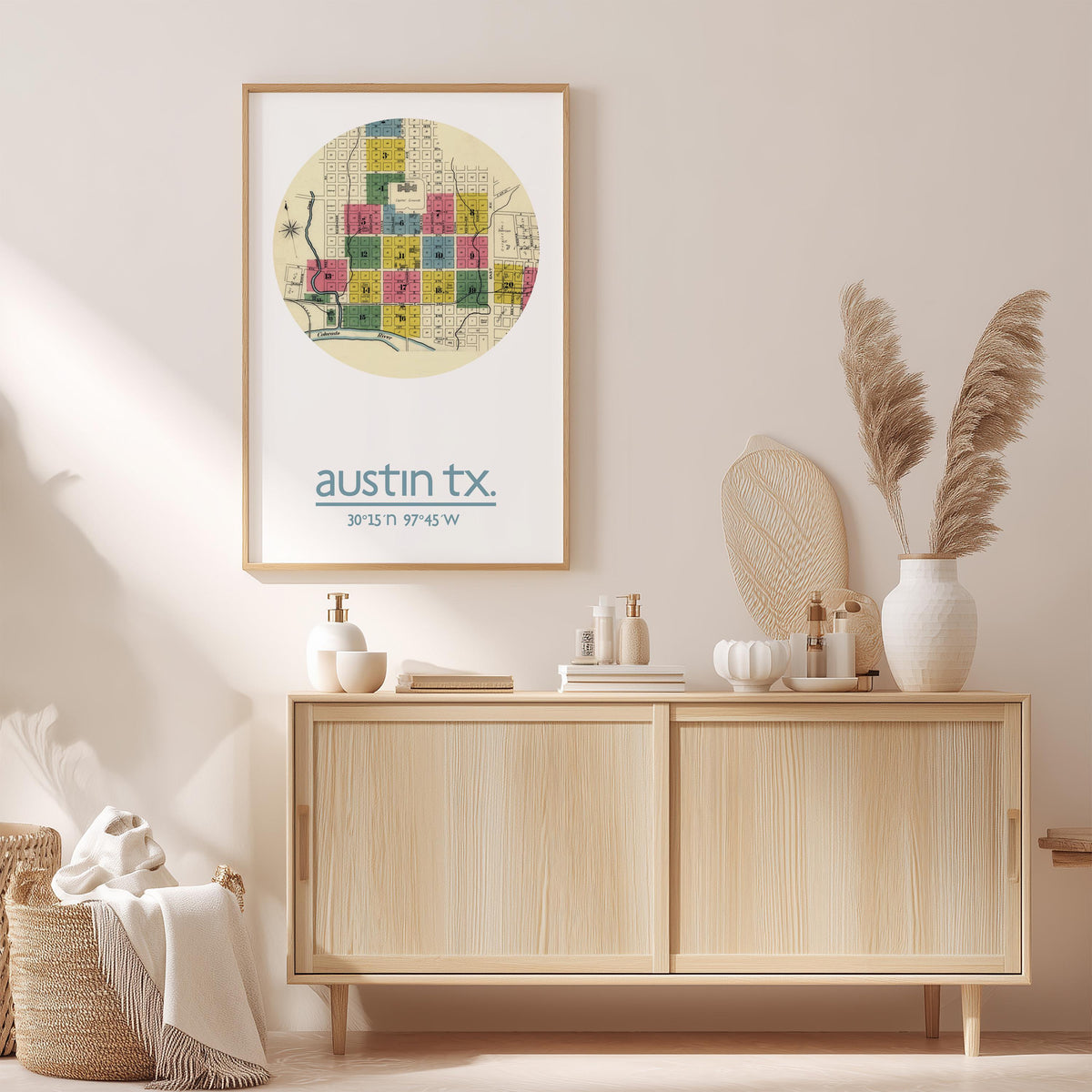 a framed map of Austin, Texas, hanging on a wall above a wooden cabinet. The cabinet has various items on it, including a vase with pampas grass, a bottle, and a bowl.