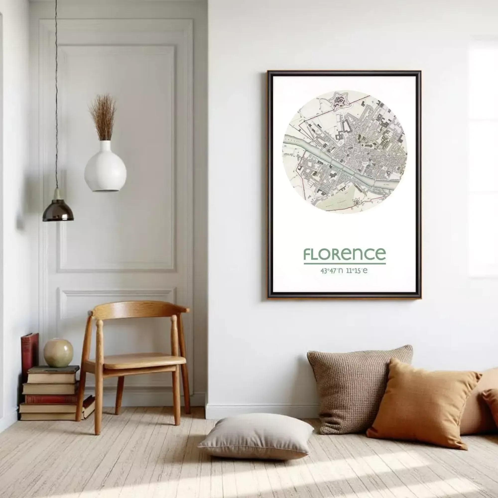 a minimalist living room with a wooden chair, a pendant light, a framed map of Florence, and a stack of books.
