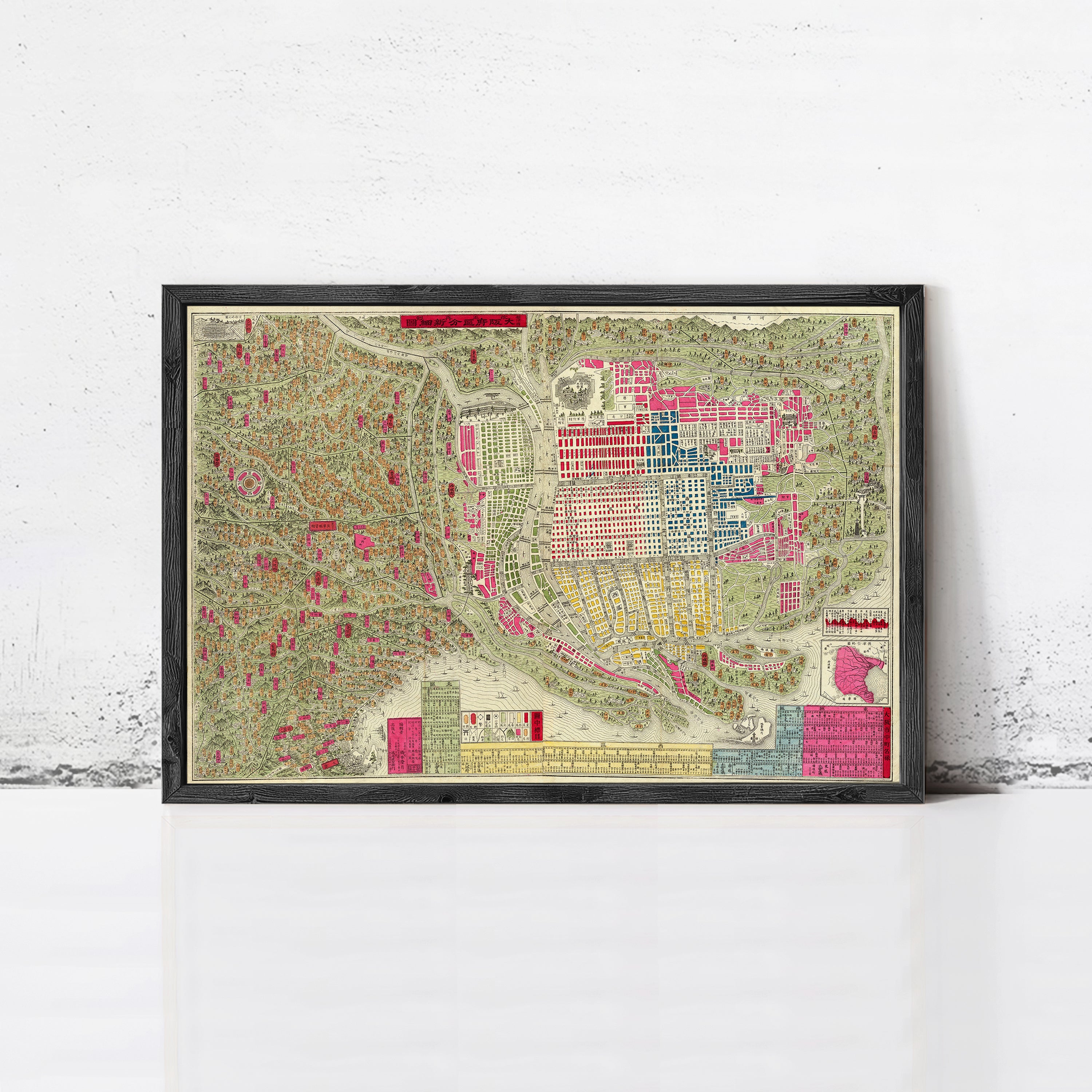 The image is a framed vintage map of a city, depicting various landmarks and streets in a colorful and detailed manner.