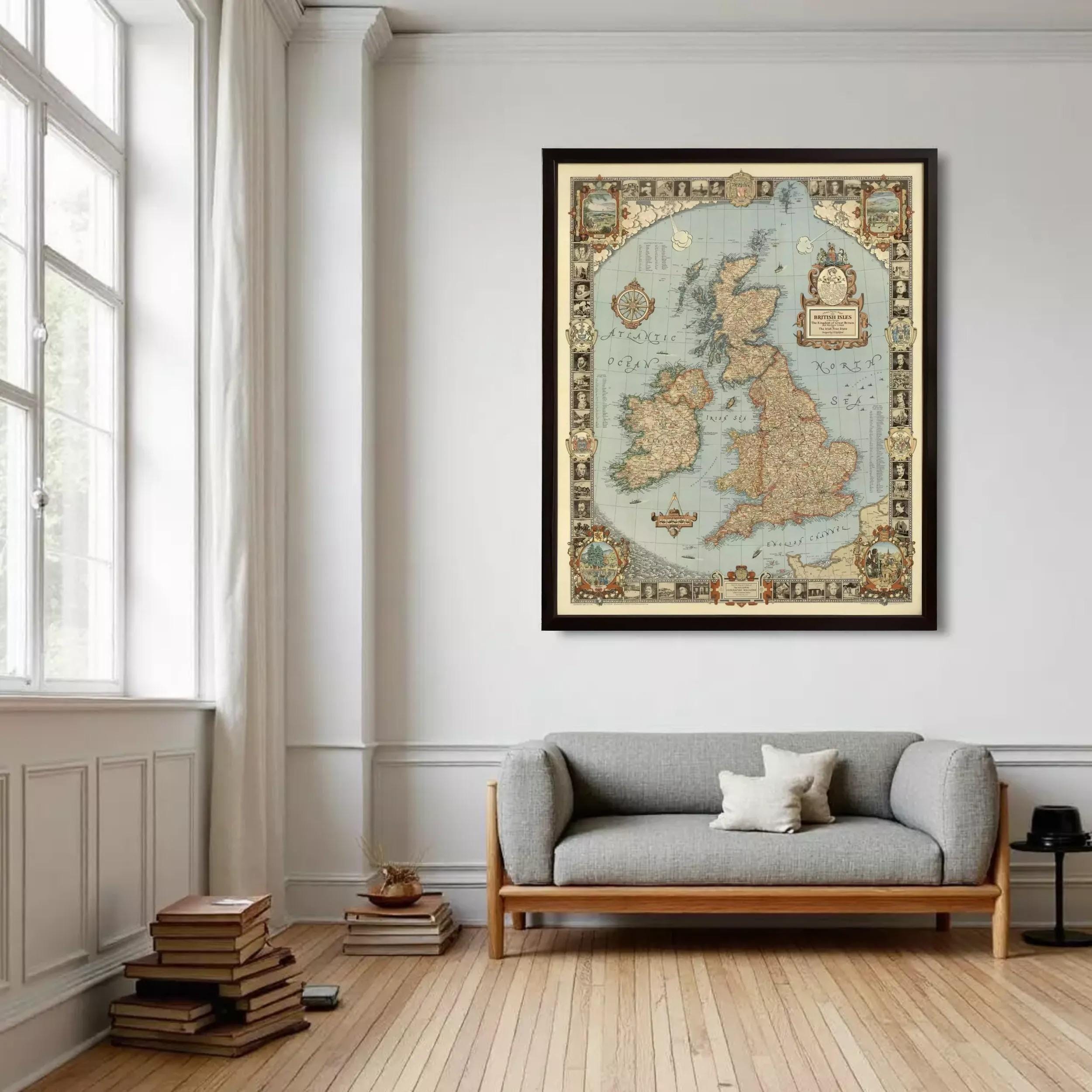 a large framed map of the United Kingdom hanging on a white wall in a room with a gray sofa and a stack of books.