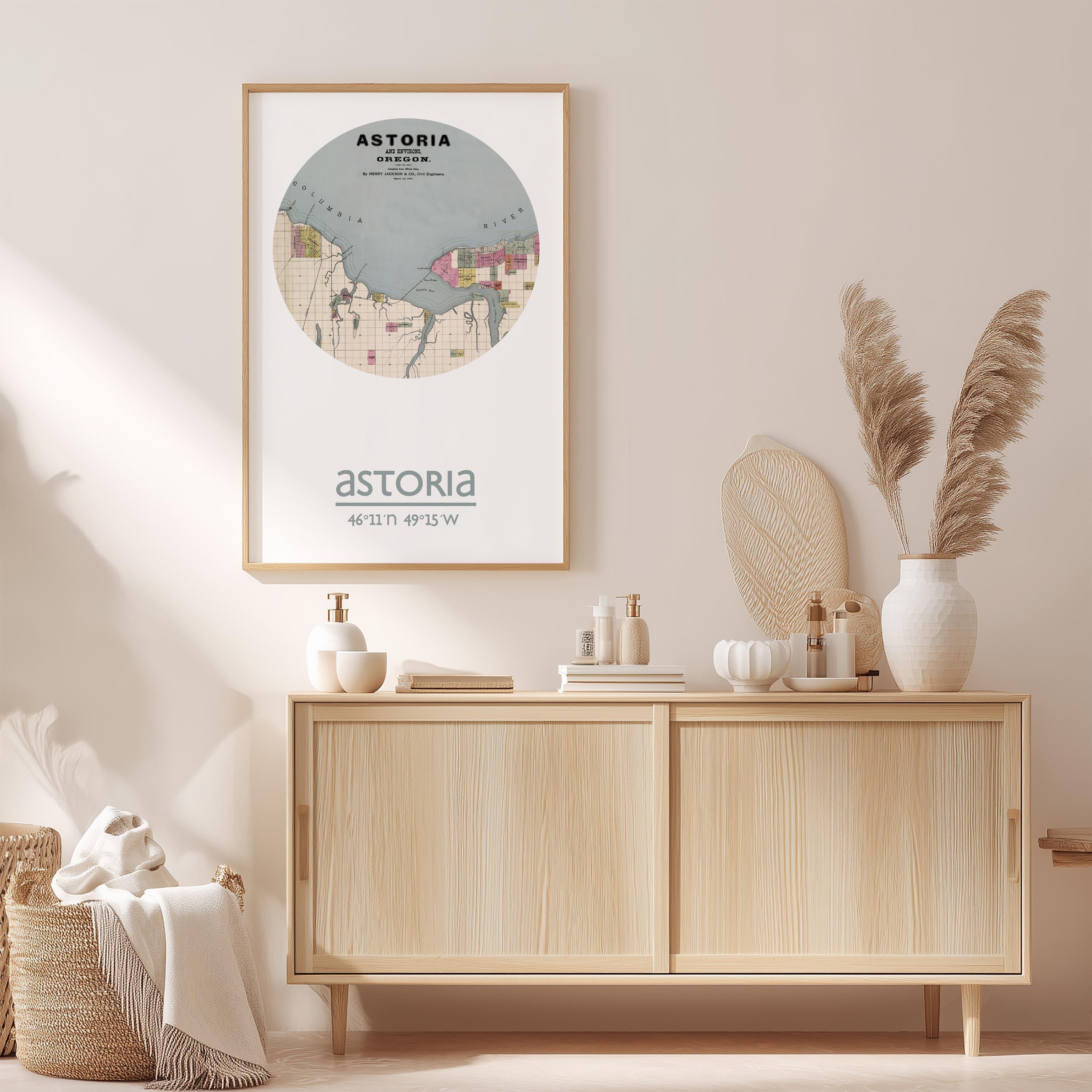 a wall-mounted poster of a map of Astoria, New York, with a wooden cabinet below it. The cabinet has various items on top, including a vase with pampas grass, a bottle, and a book.