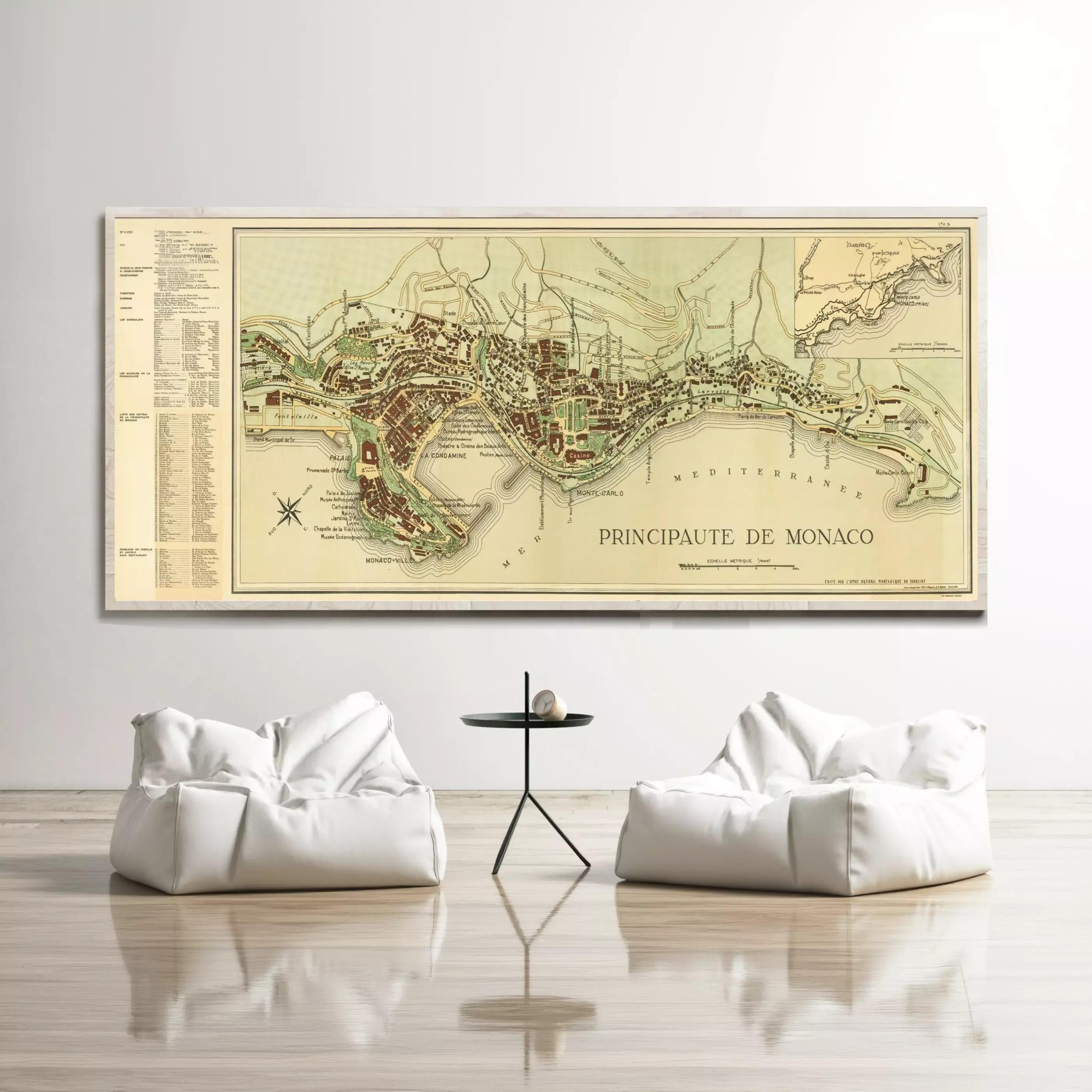 a large map of Monaco, a French island, hanging on a wall above two white bean bag chairs and a small black table.