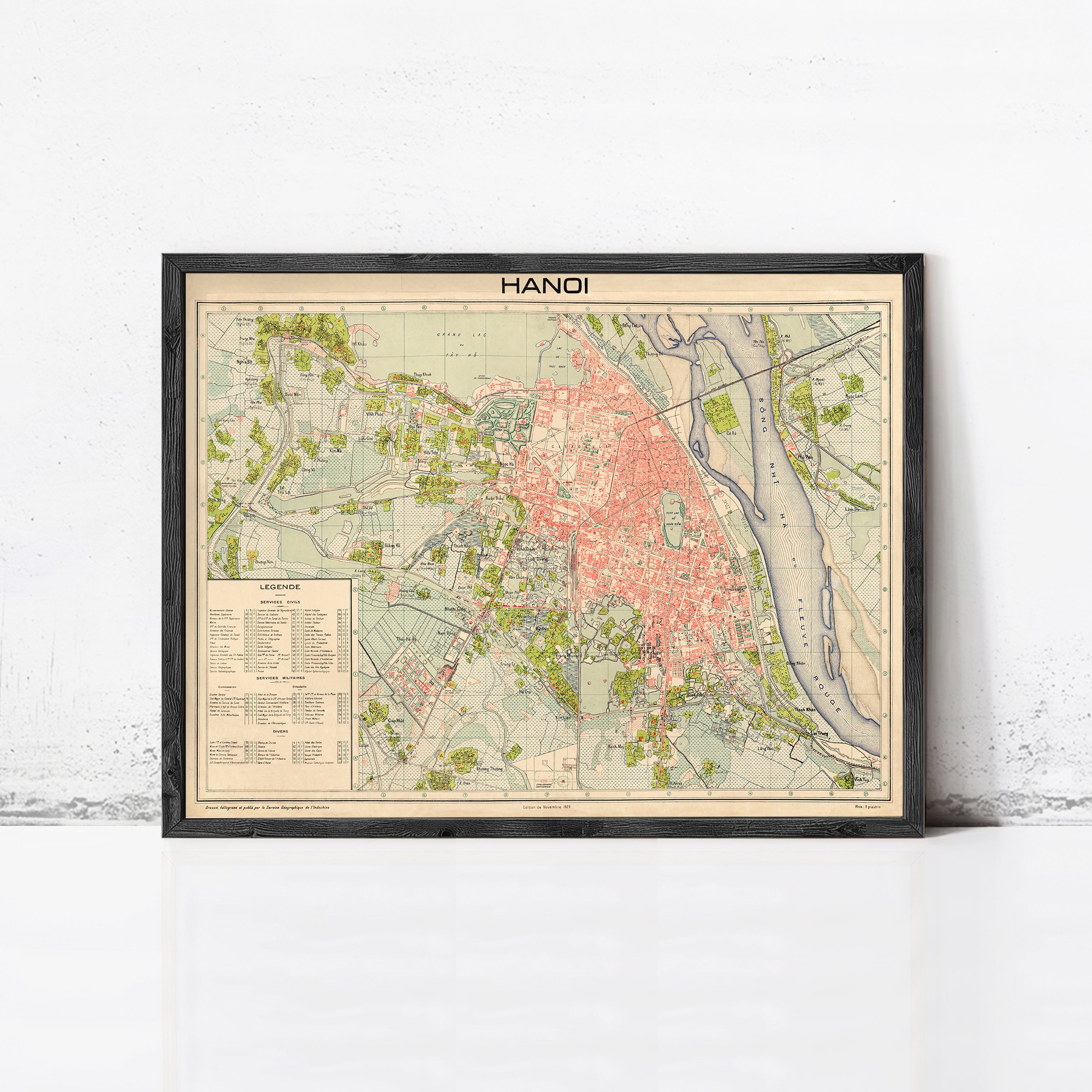 The image is a framed vintage map of Hanoi, Vietnam, depicting the city's streets, landmarks, and surrounding areas.