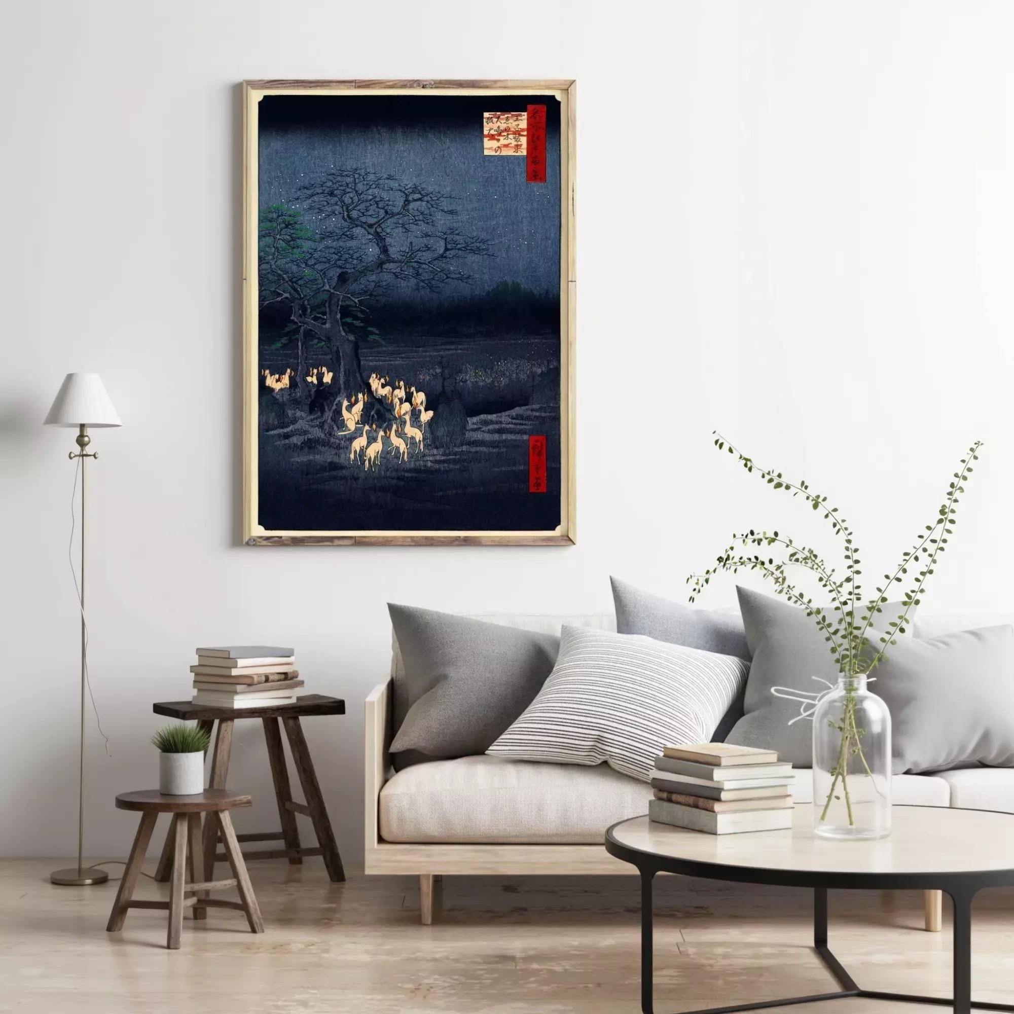a cozy living room with a large framed artwork of a nighttime landscape hanging on the wall, featuring a dark blue background with a tree and glowing yellow lights. The room is furnished with a gray sofa, a wooden side table, and a black coffee table with a vase of greenery.