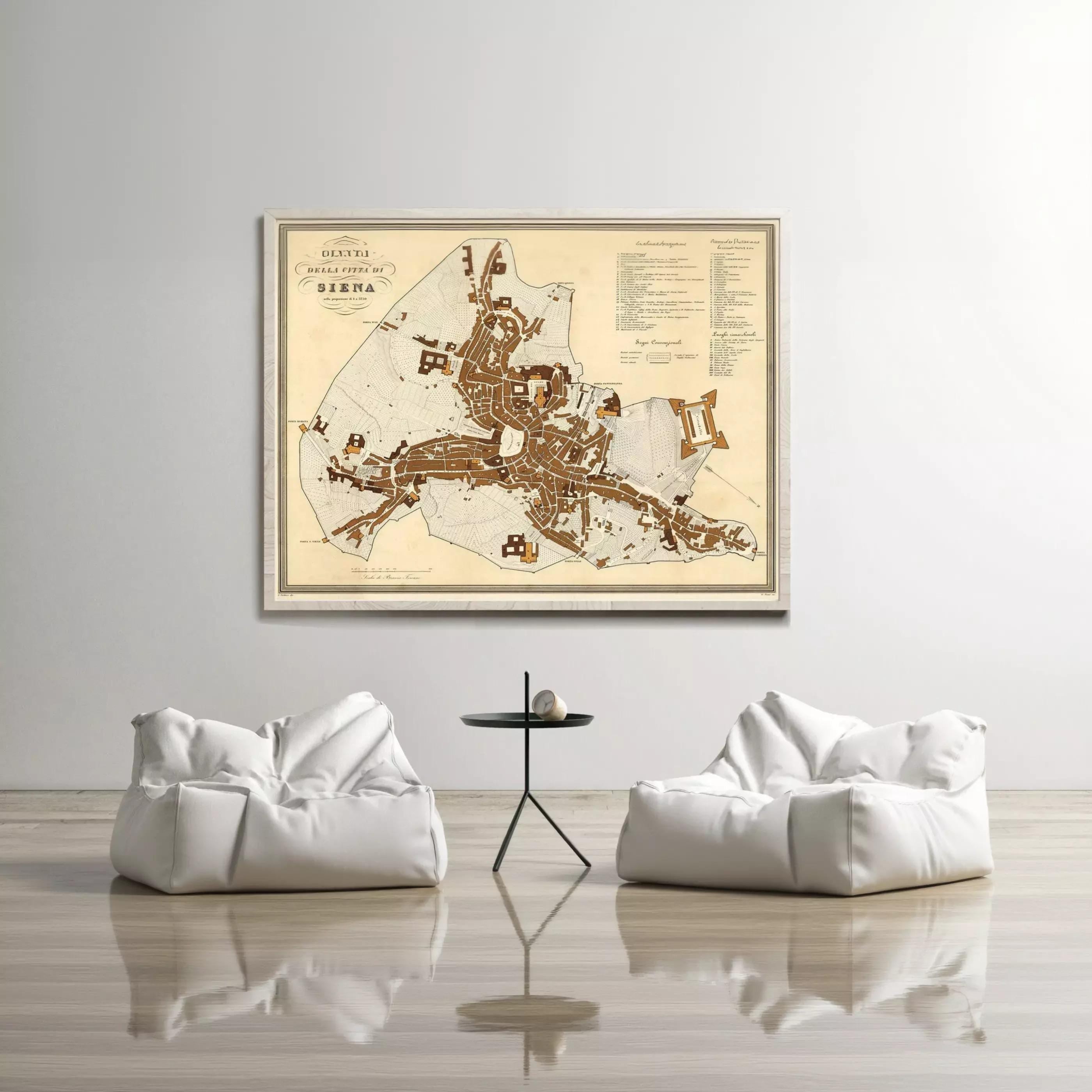 a large framed map of Siena, Italy, hanging on a white wall above two white bean bag chairs and a small black table.