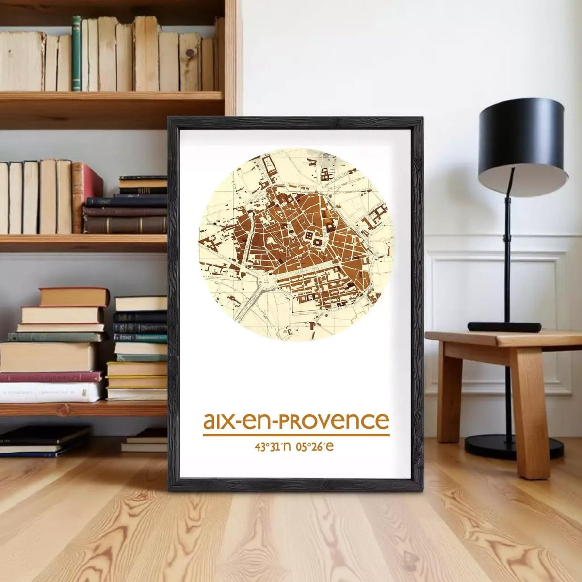 A framed map of Aix-en-Provence, France, with the text "aix-en-Provence" and "43°N 05°E" printed on it, is displayed on a wooden floor in front of a bookshelf.