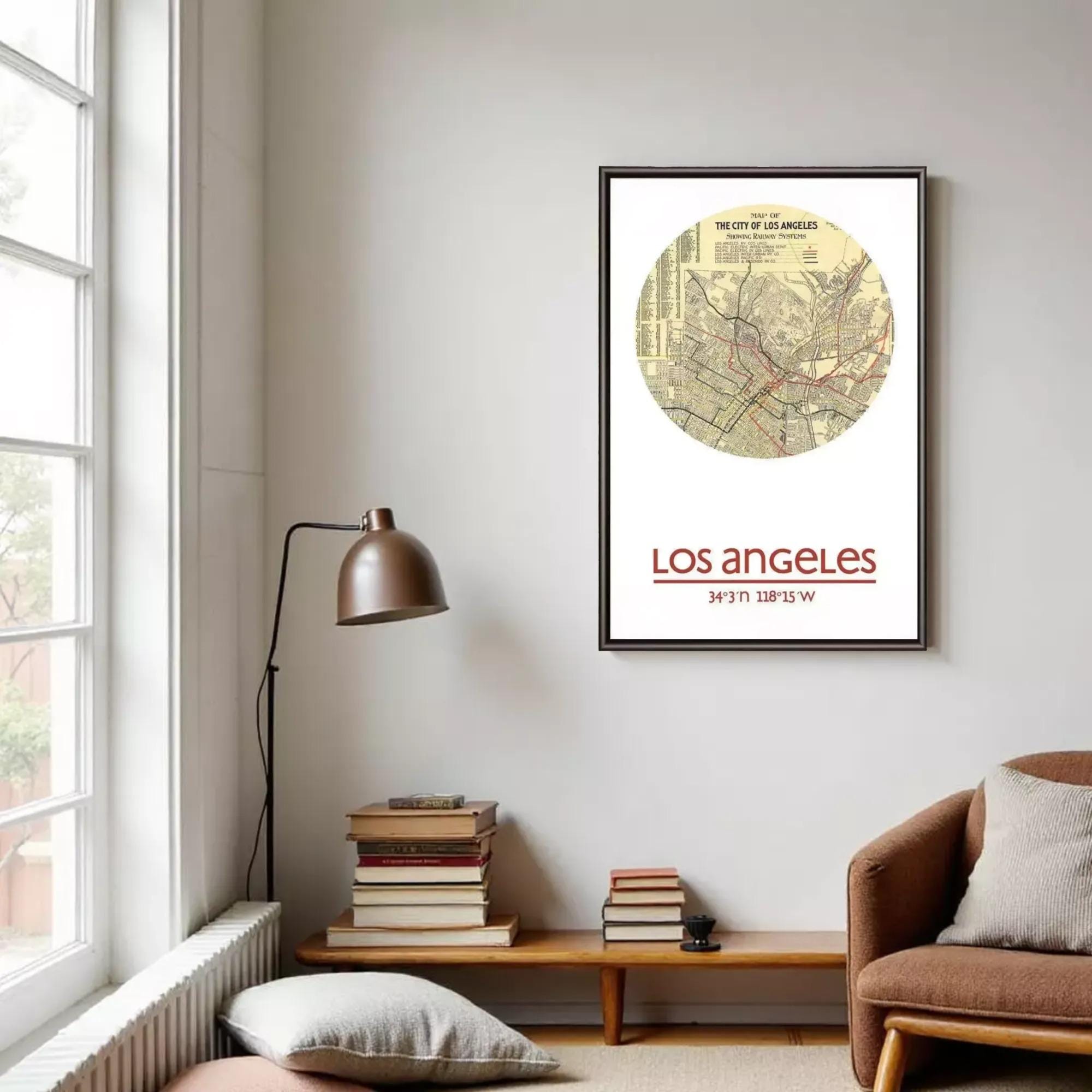 a framed map of Los Angeles, with the text "LOS ANGELES" and "34°37'11" 38°15'8" W" visible. The map is displayed on a wall in a living room setting, with a lamp, books, and a chair visible in the foreground.