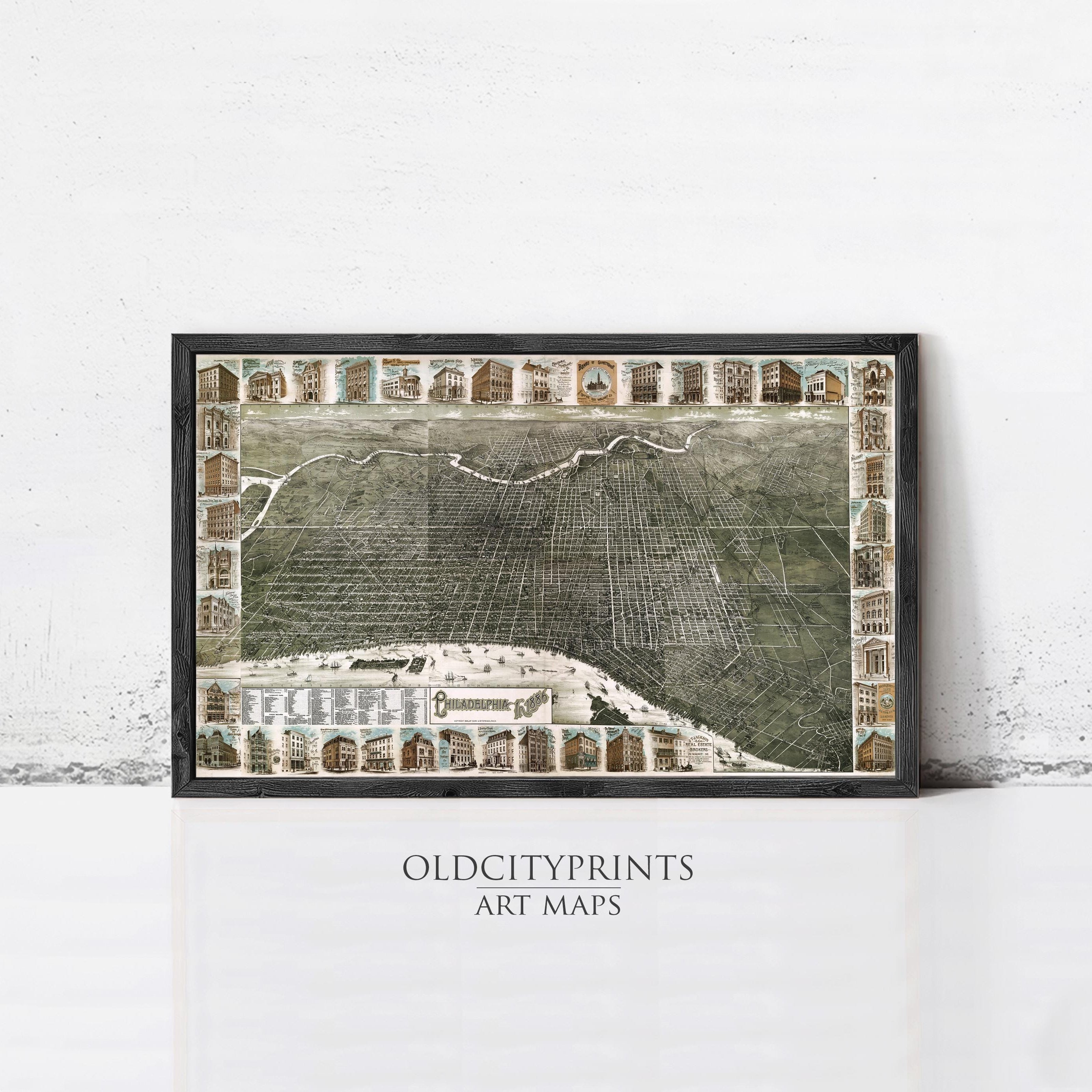The image is a framed art print depicting a detailed map of a city, with various buildings and landmarks represented in a collage-like manner.