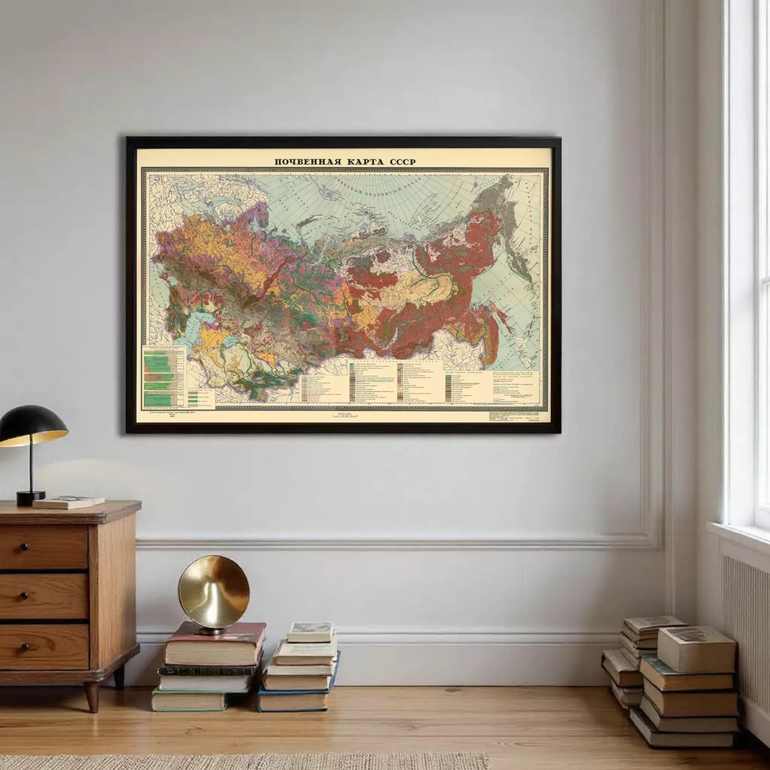 a large framed map of Russia hanging on a wall, with a wooden dresser and a stack of books in the foreground.