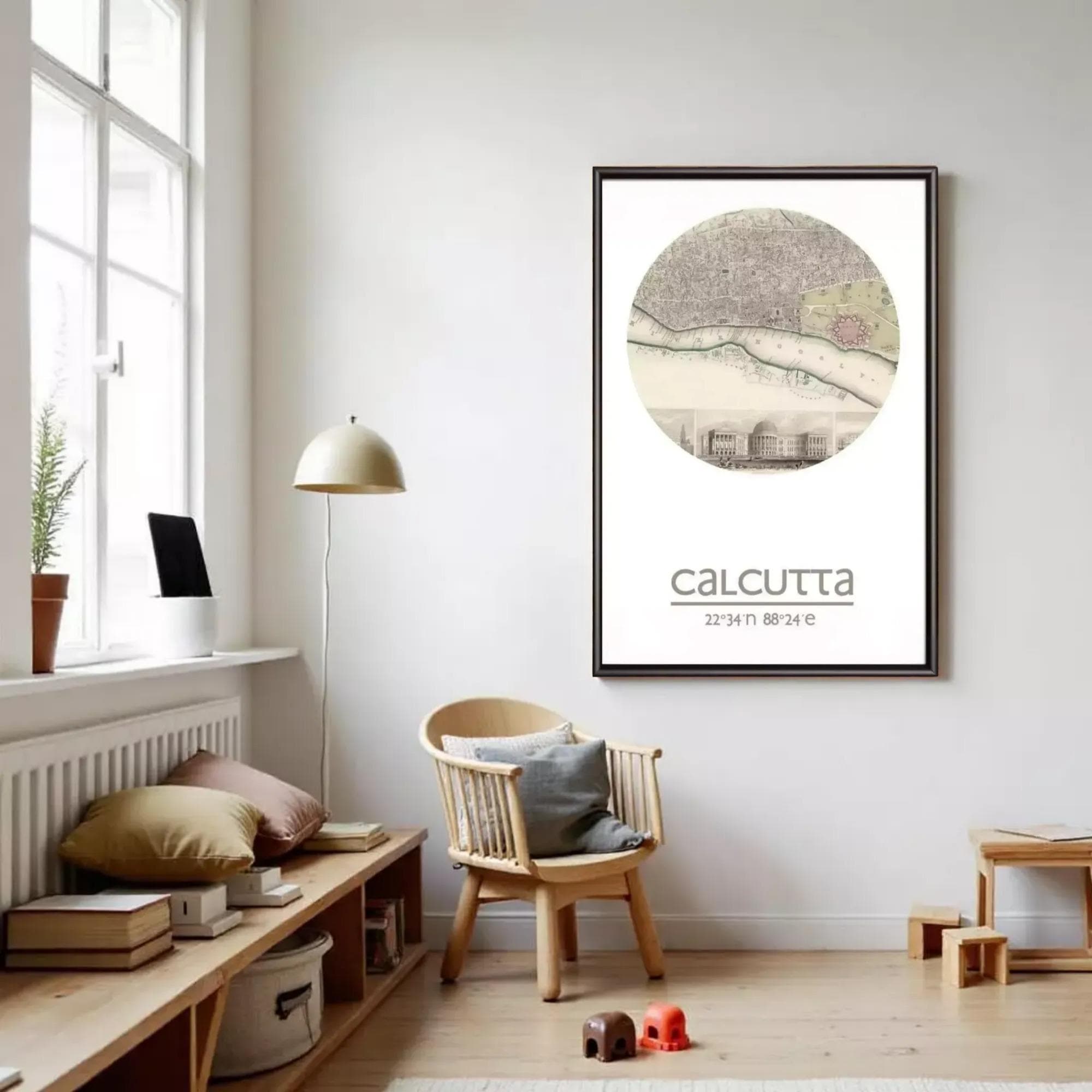 a cozy living room with a large framed map of Calcutta hanging on the wall. The room has a wooden floor, a wooden bench, a wooden chair, and a small table with a lamp. There are also some books and a potted plant in the room.