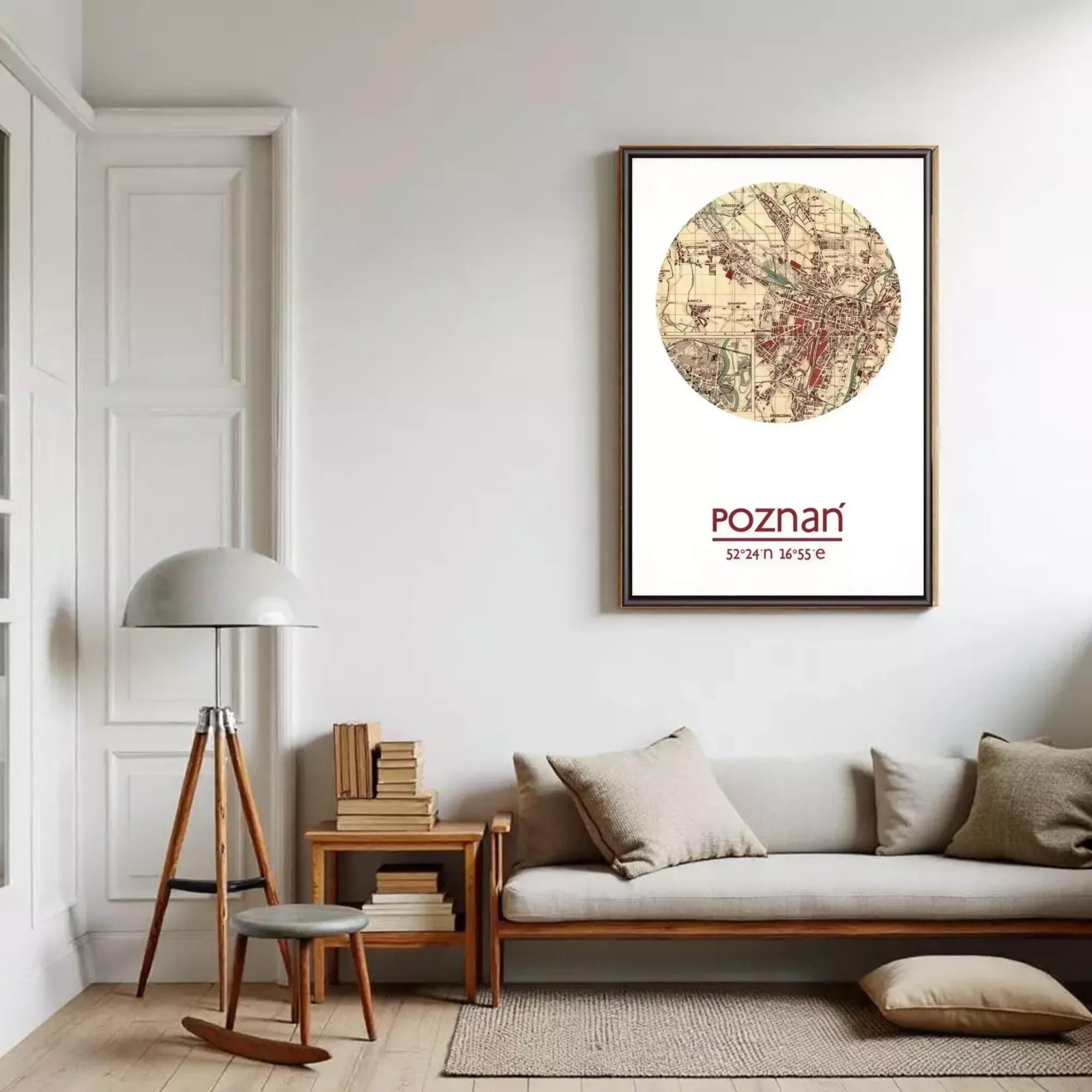 a living room with a large circular map of Poznan hanging on the wall, a wooden side table with a lamp, a sofa with pillows, and a bookshelf filled with books.