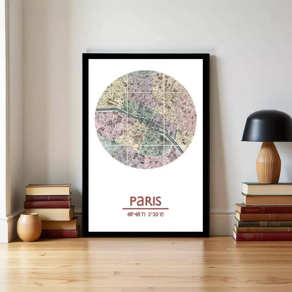 A framed map of Paris, with a colorful and detailed representation of the city, is displayed on a wall next to a stack of books and a lamp.