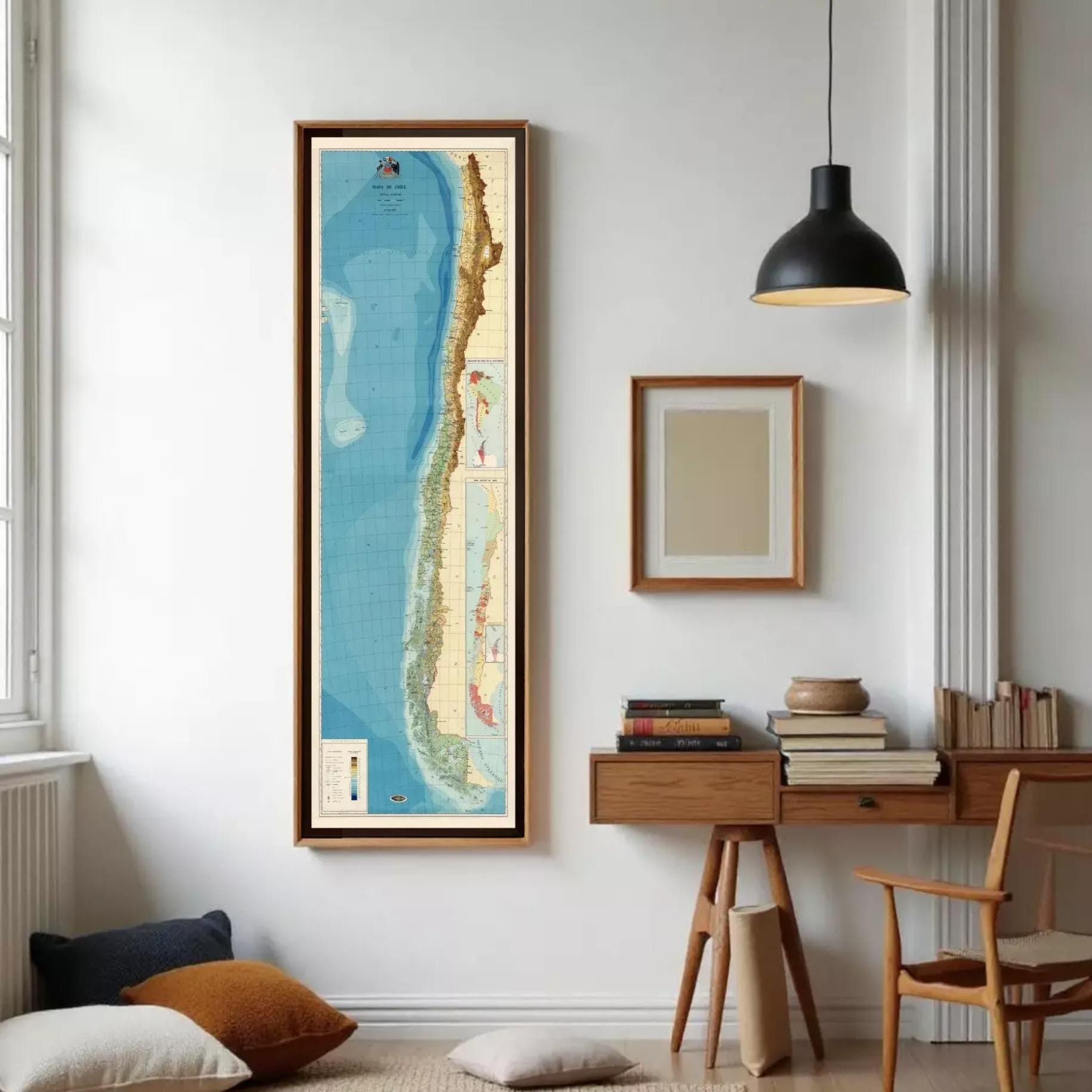 a tall, narrow framed map of South America, specifically Chile, standing against a white wall.
