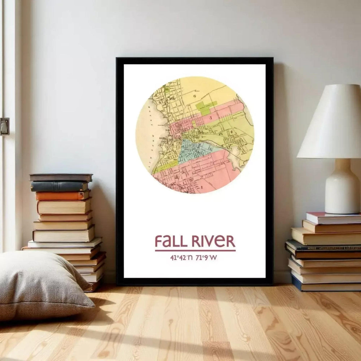 A framed map of the fall river is displayed on a wall, with a stack of books and a lamp to the side.