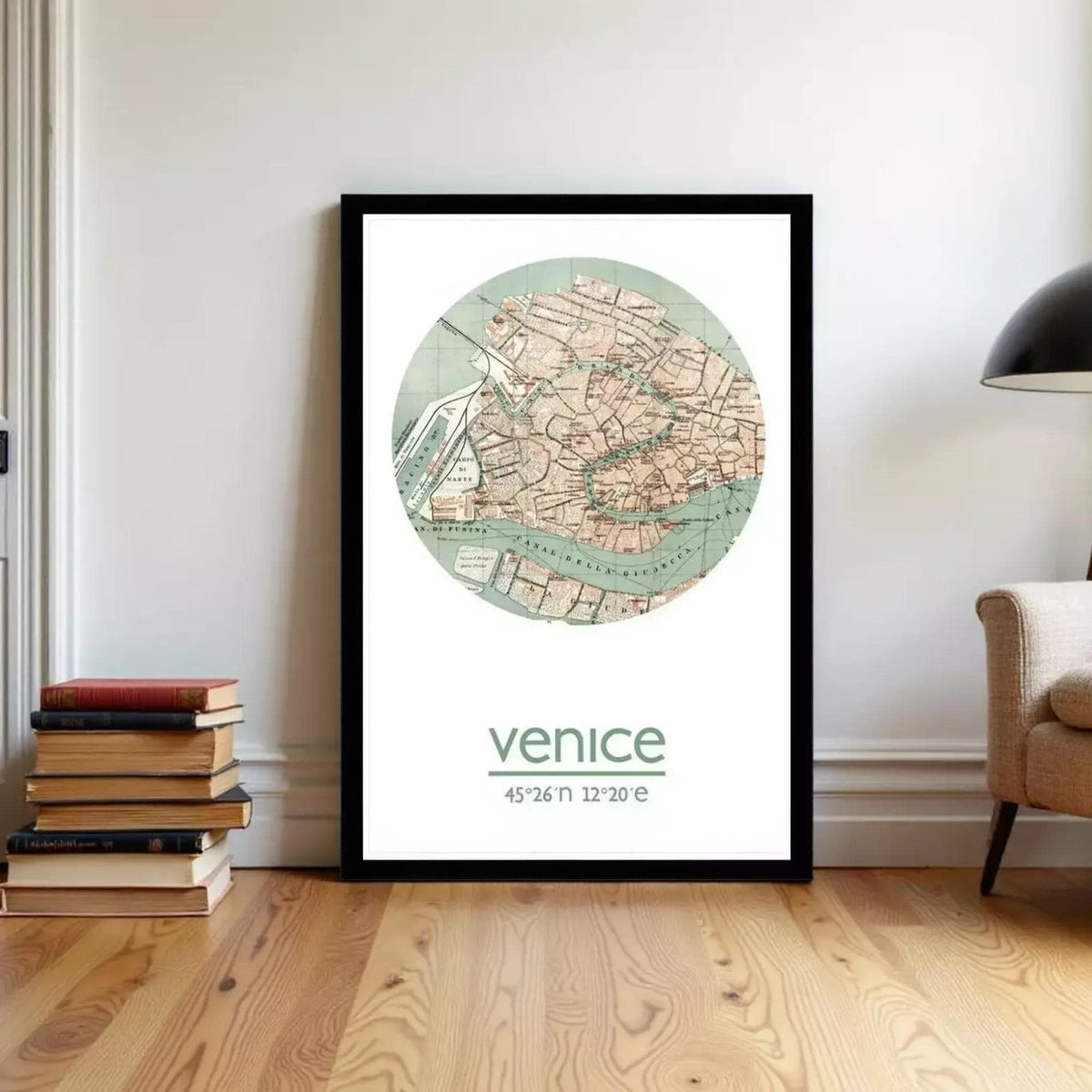 A framed map of Venice, Italy, with the word venice' written below it, is displayed on a wall in a room with a stack of books and a lamp.