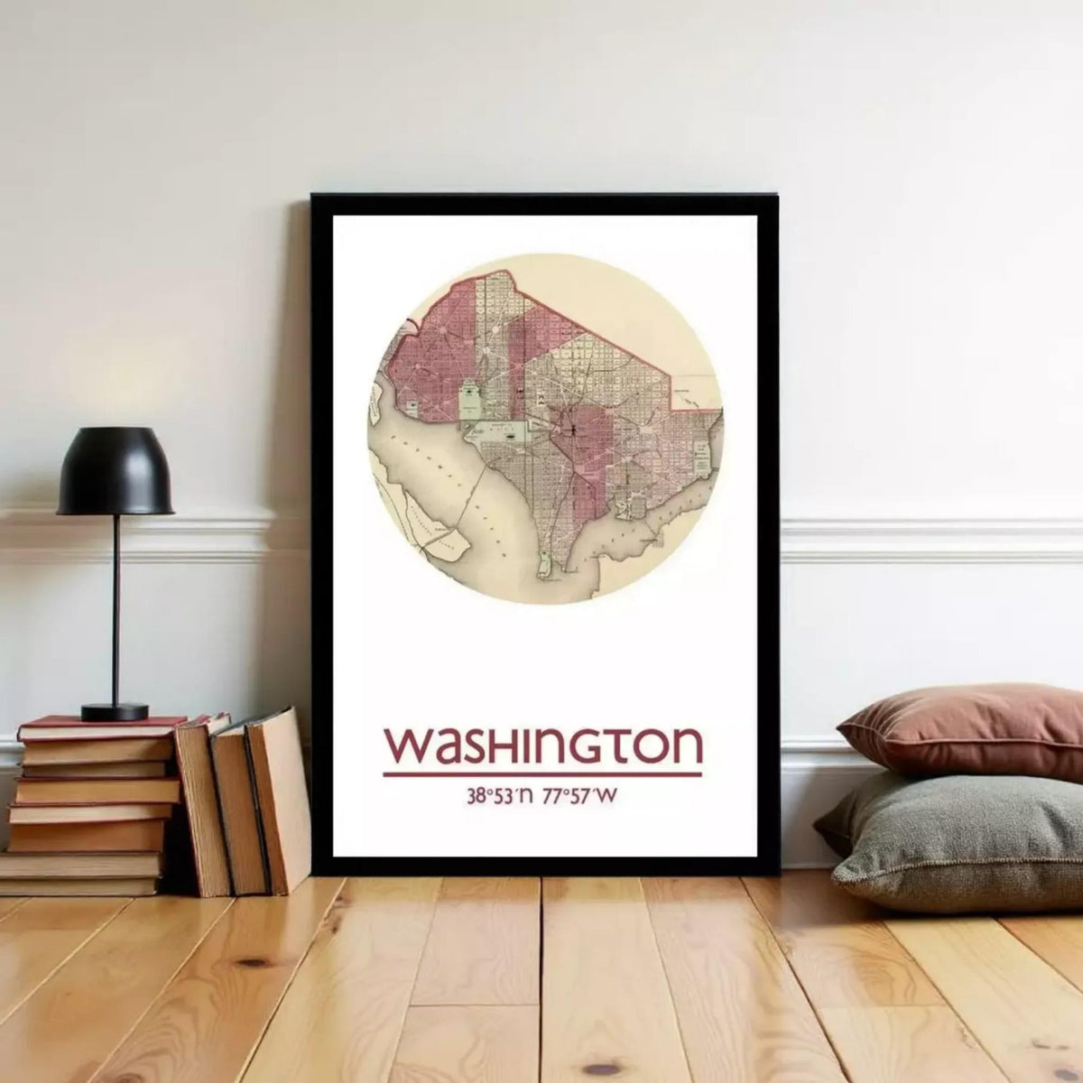 A framed map of Washington, D.C., with the city's location and coordinates displayed, is hanging on a wall next to a stack of books and a lamp.