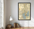 a framed map of Tampa, Florida, hanging on a wall in a room with a lamp, books, and a window.