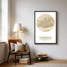 a framed map of Liverpool, with a lamp and a stack of books on the floor in front of it.