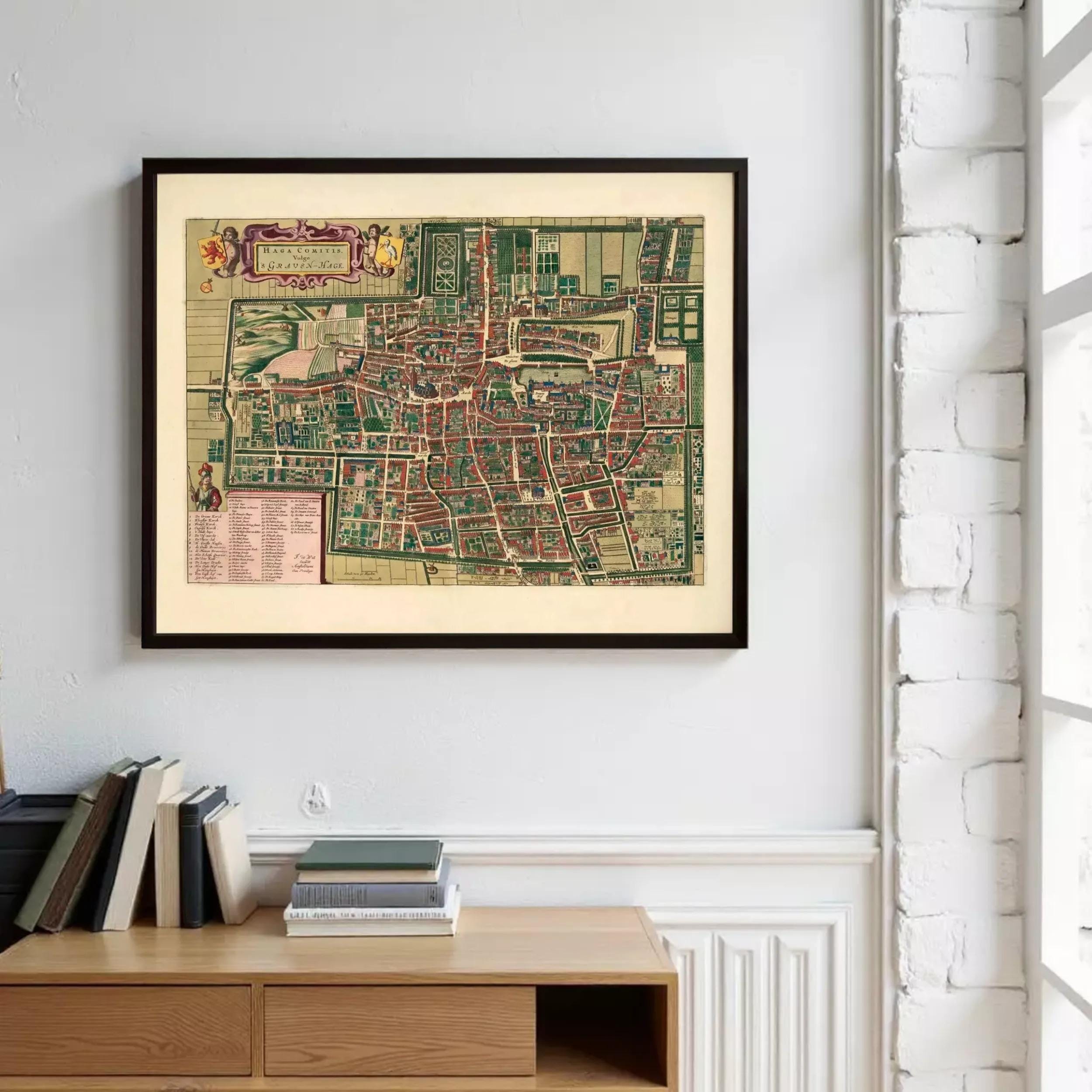 a framed map of a city hanging on a wall, with a wooden dresser below it and a stack of books on top.