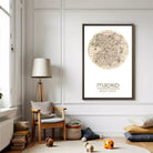 a cozy living room with a large framed map of Madrid hanging on the wall, a wooden chair, a lamp, and a stack of books.