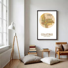 a cozy living room with a large framed map of Columbus, Ohio, hanging on the wall. The room has a wooden floor, a lamp, a chair, and a stack of books.