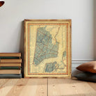 The image is a framed vintage map of New York City, depicting the city's streets and neighborhoods in a detailed and colorful manner.