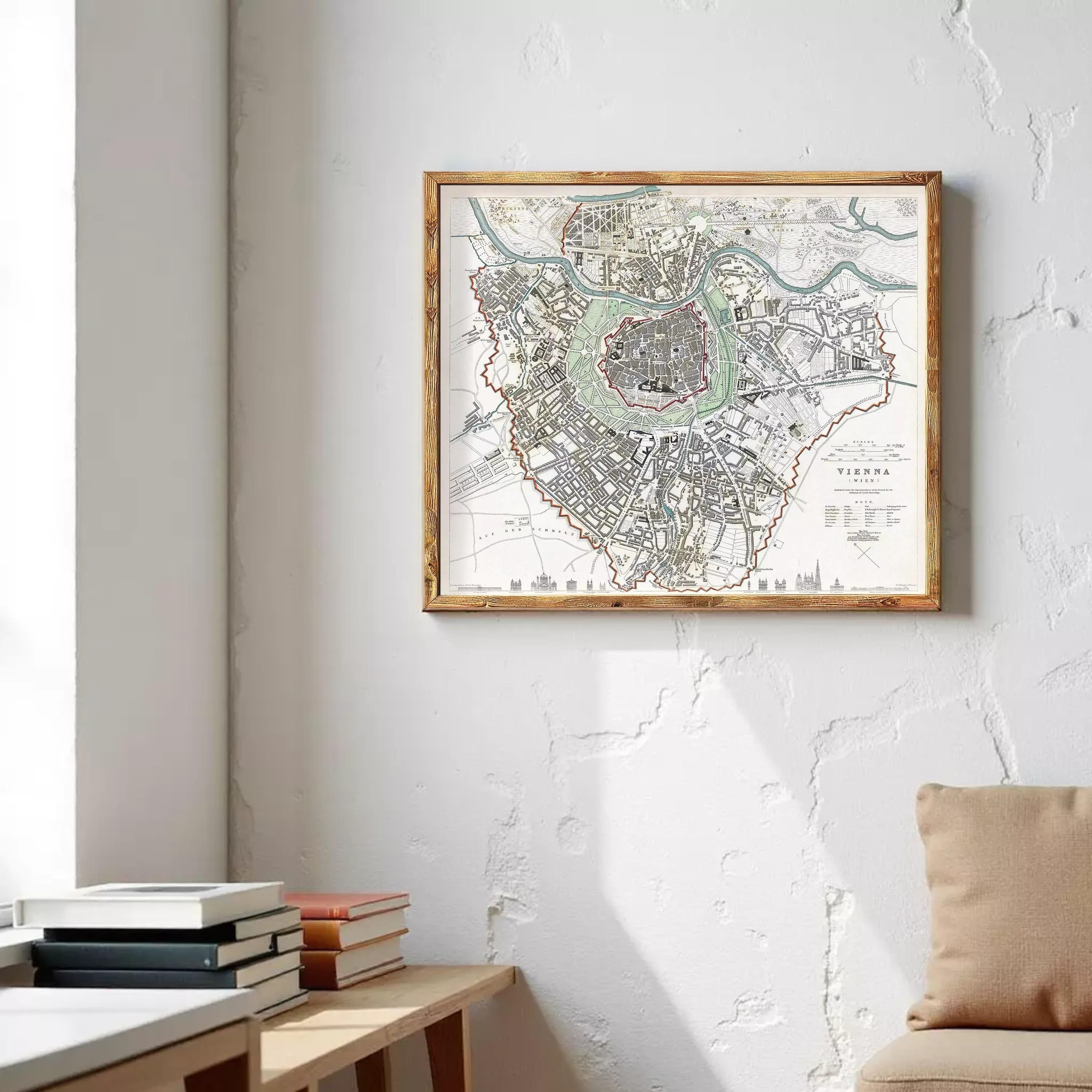 a framed map of Vienna, Austria, hanging on a wall in a room with a wooden table and a stack of books.