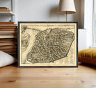The image is a framed antique map of a city, likely from the 16th century, depicting a detailed layout of the city's streets and surrounding areas.