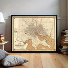 a framed antique map of Baltimore, Maryland, with a wooden floor and a stack of books in the background.