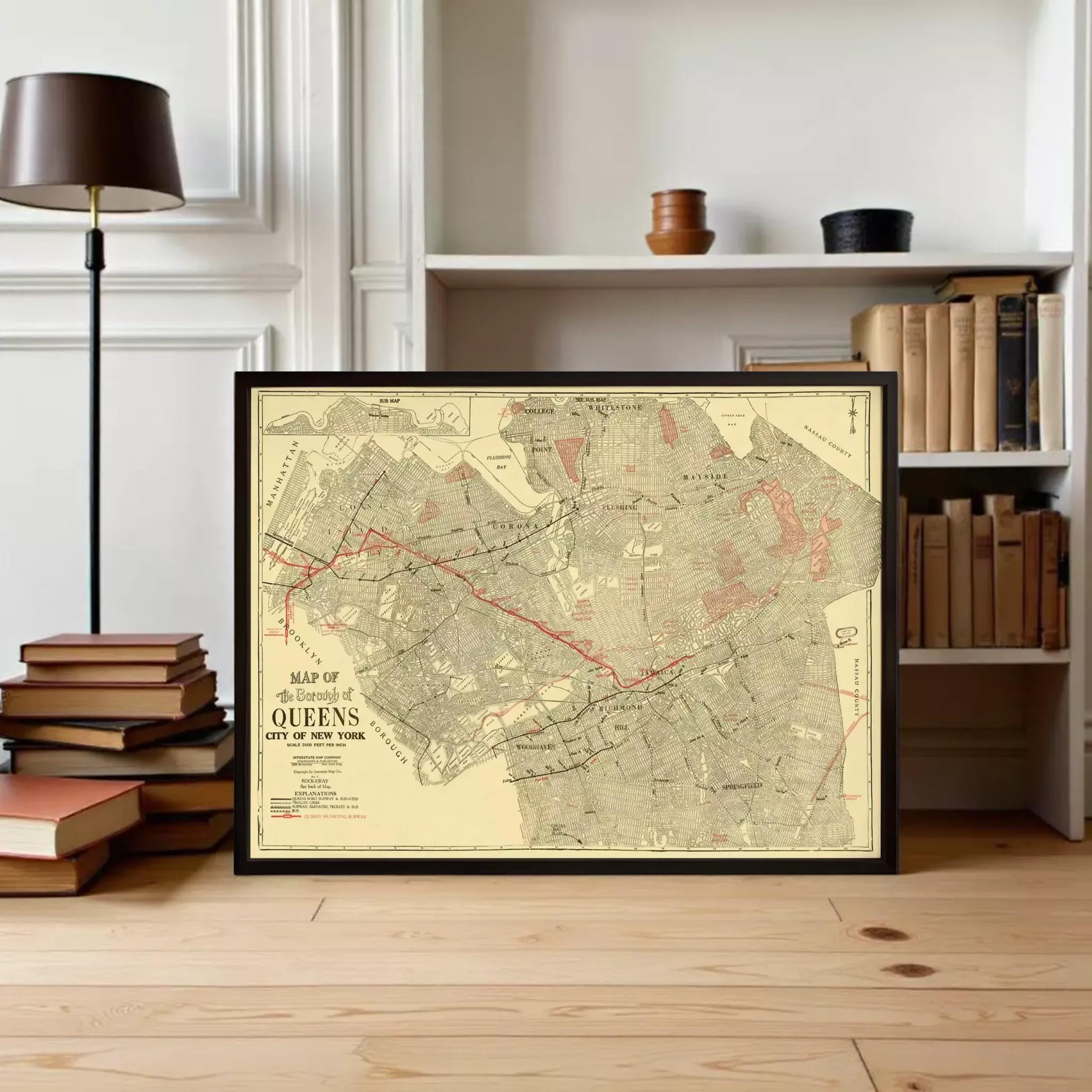 A framed map of the city of New York is displayed on a wooden floor in front of a bookshelf filled with books.