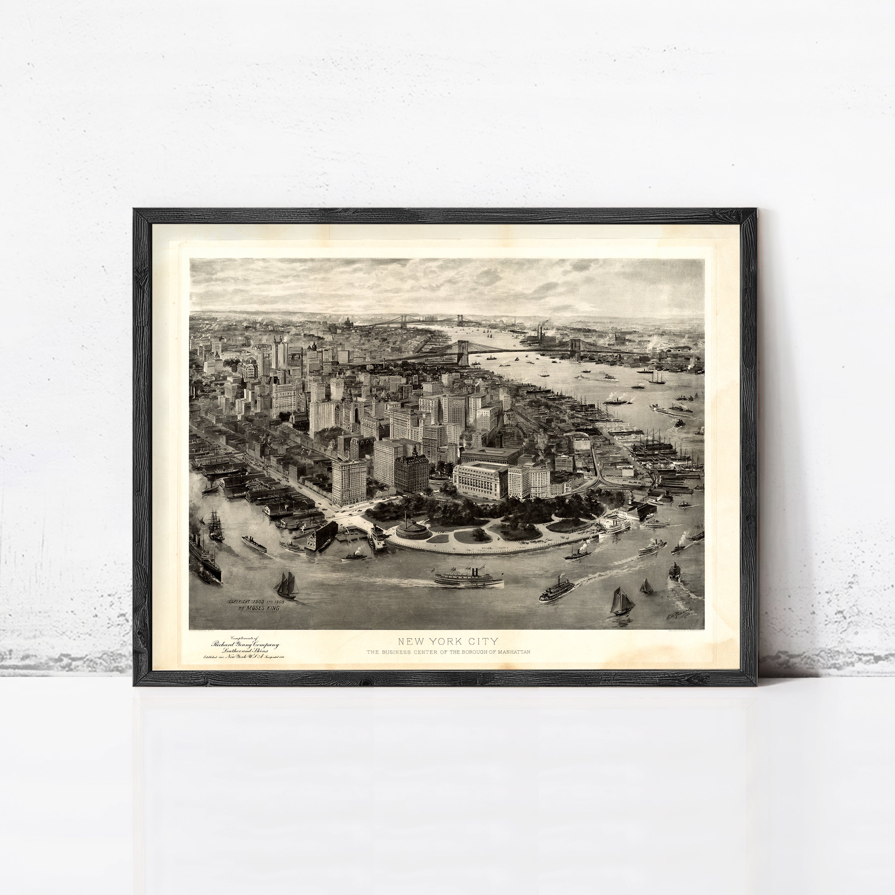 The image is a framed black and white photograph of the New York City skyline, showcasing the city's iconic buildings and waterways.