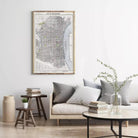 a living room with a large framed map of Philadelphia hanging on the wall above a couch with pillows. There are also some books and a vase with flowers on the couch, creating a cozy and inviting atmosphere.